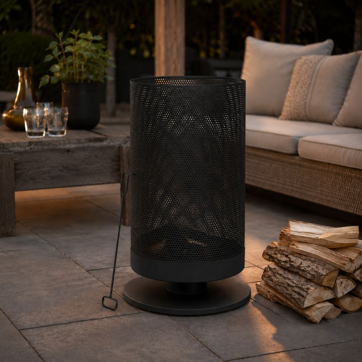 A black metal outdoor fireplace with firewood beside it on a patio.