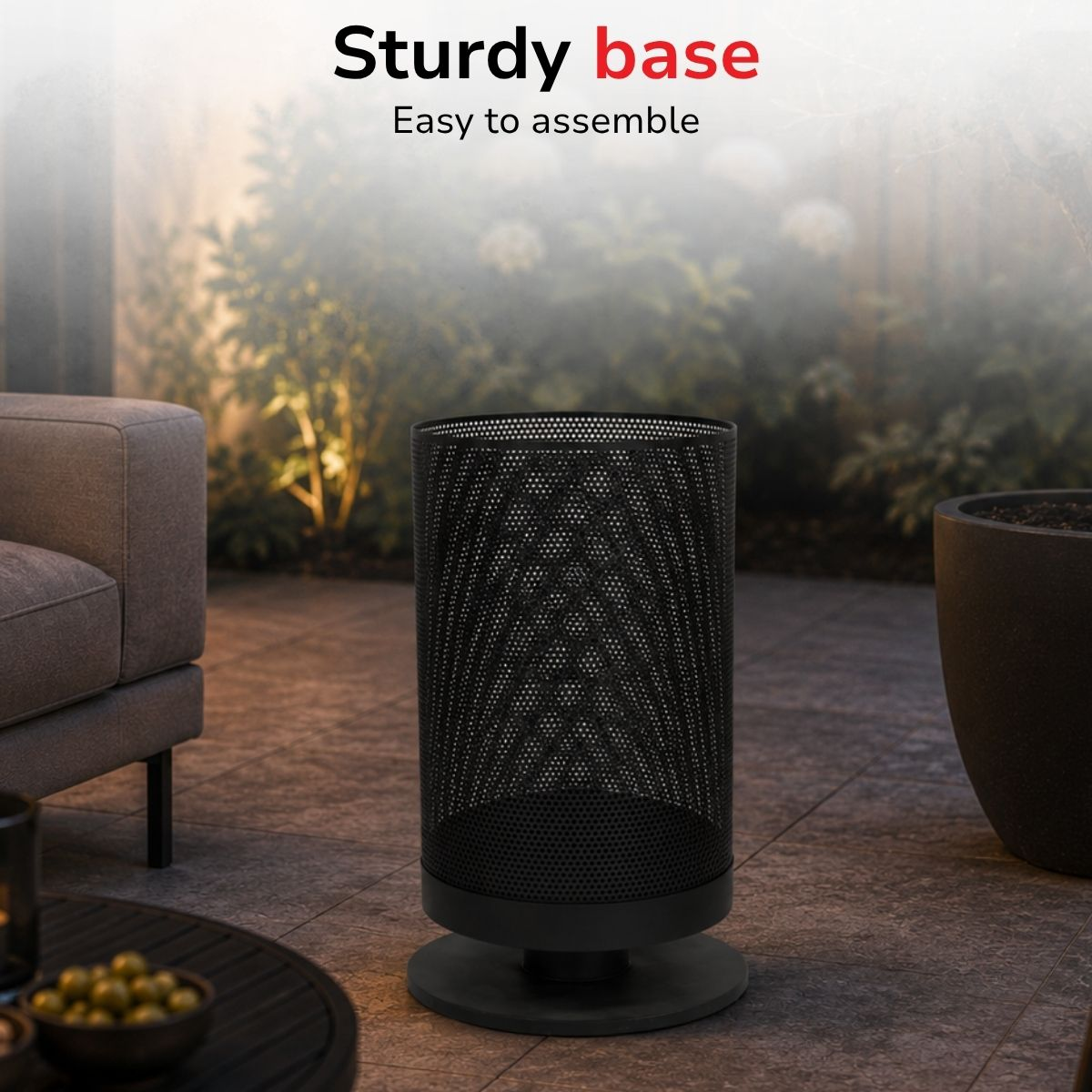 Black metal basket with perforated pattern on a round base outdoors.