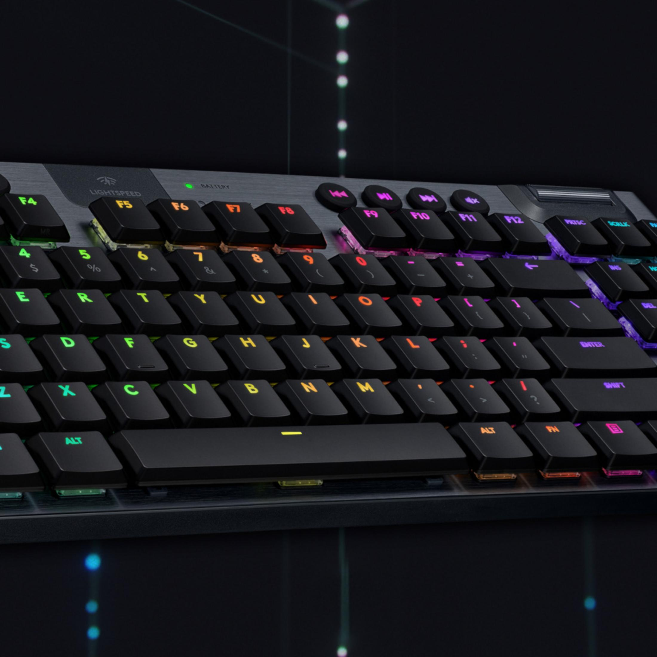 Un primer plano de un teclado negro con teclas iluminadas RGB sobre fondo oscuro.