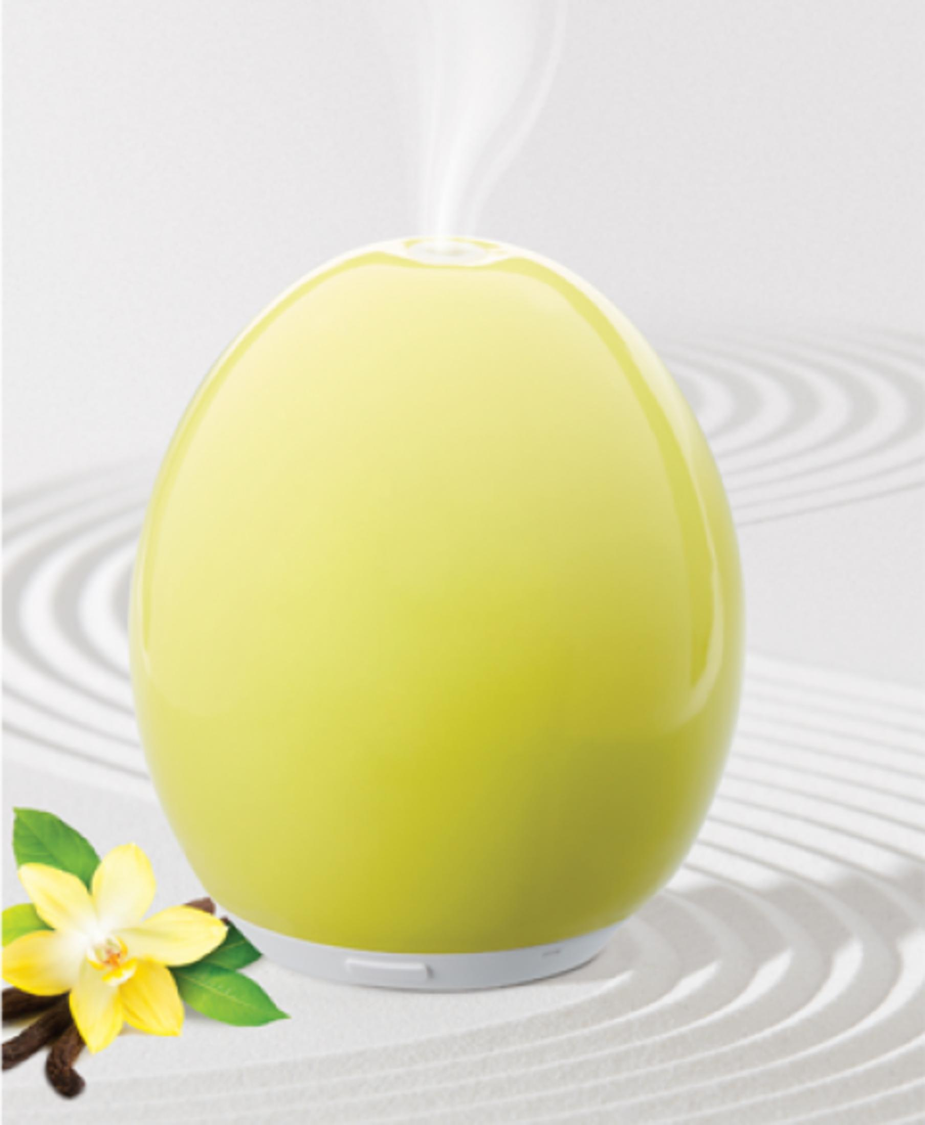 Ein gelber, eiförmiger Diffusor gibt Dampf neben einer gelben Blume und Vanilleschoten ab.