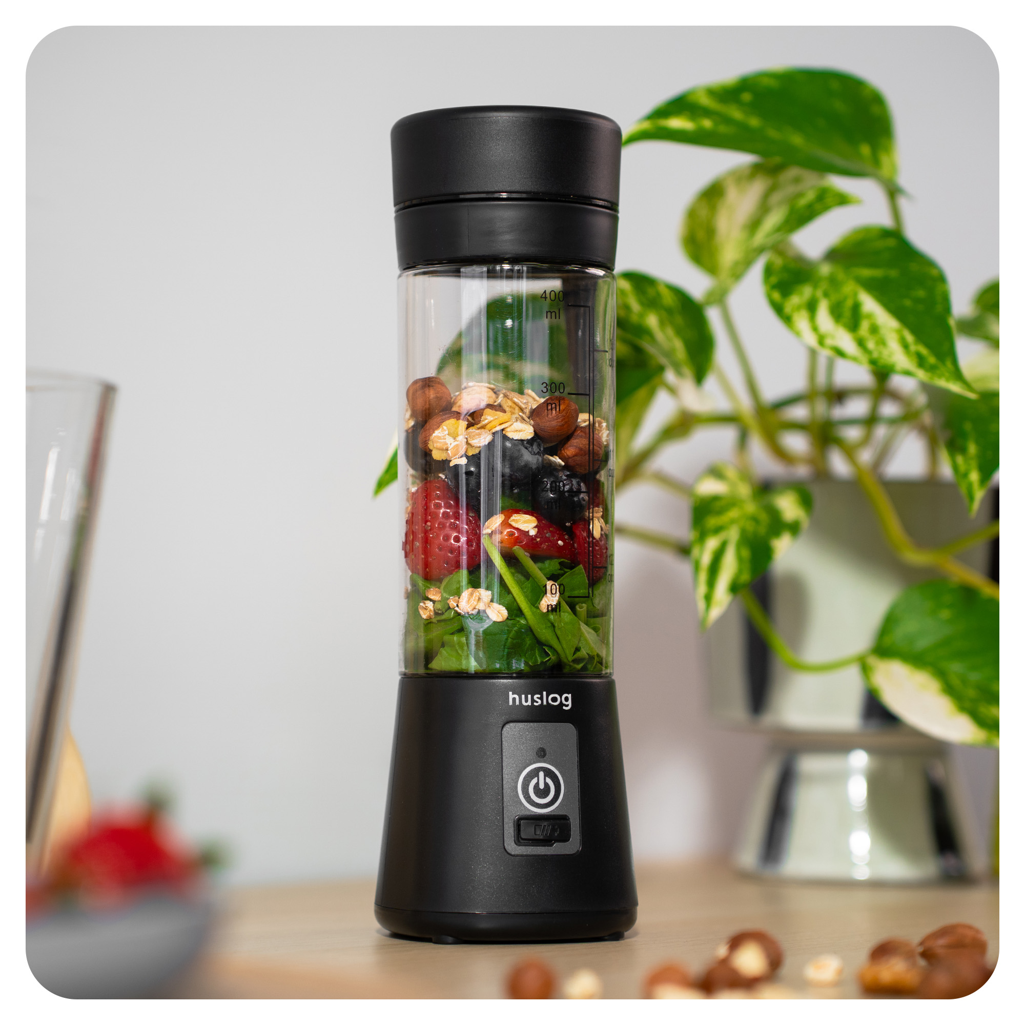 Czarny przenośny blender wypełniony truskawkami, jagodami, płatkami owsianymi i szpinakiem.