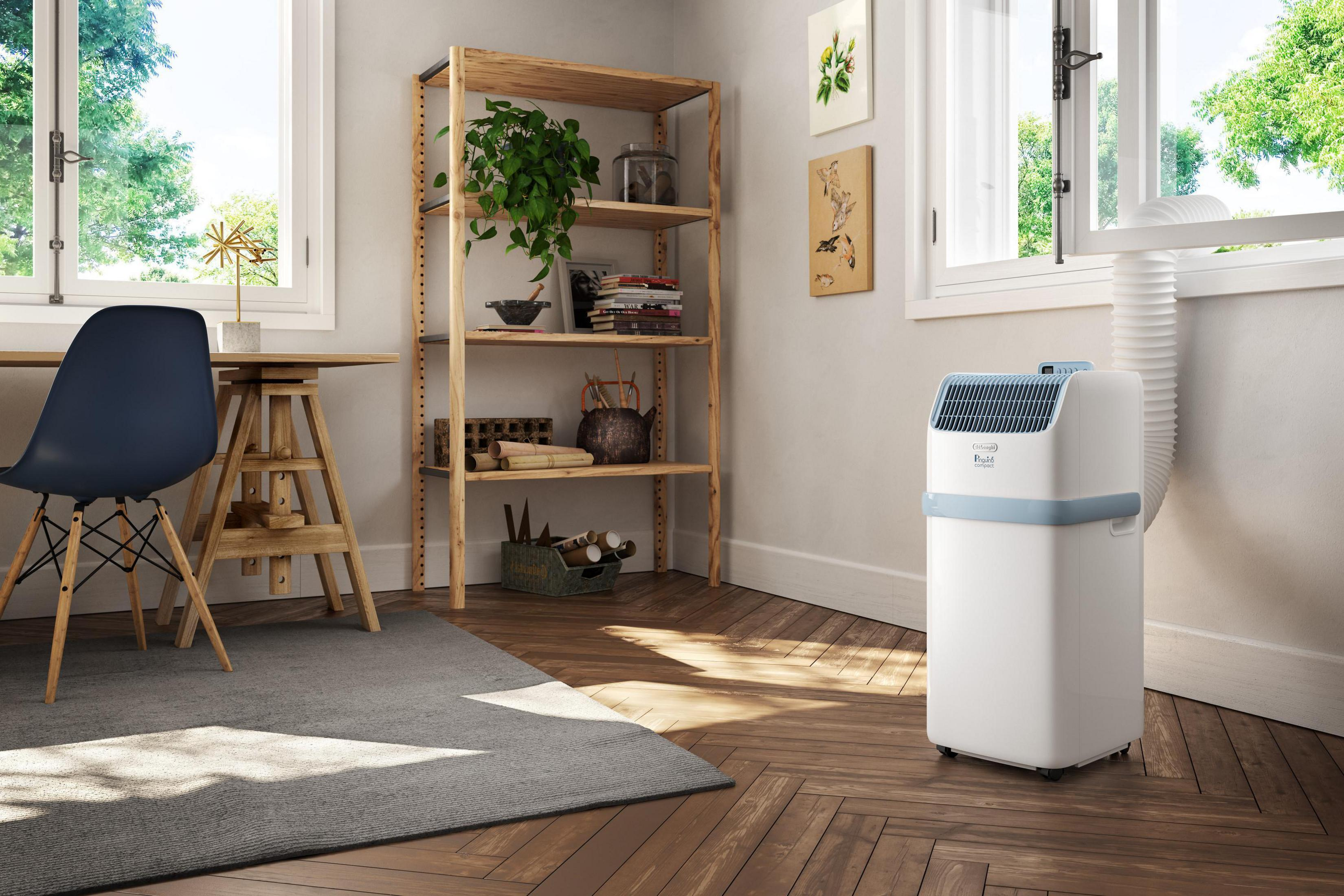 Un condizionatore portatile vicino a una finestra su un pavimento in legno.