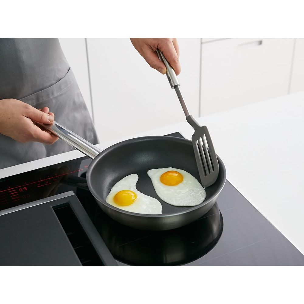 Due uova fritte vengono cotte in una padella su un piano cottura a induzione.