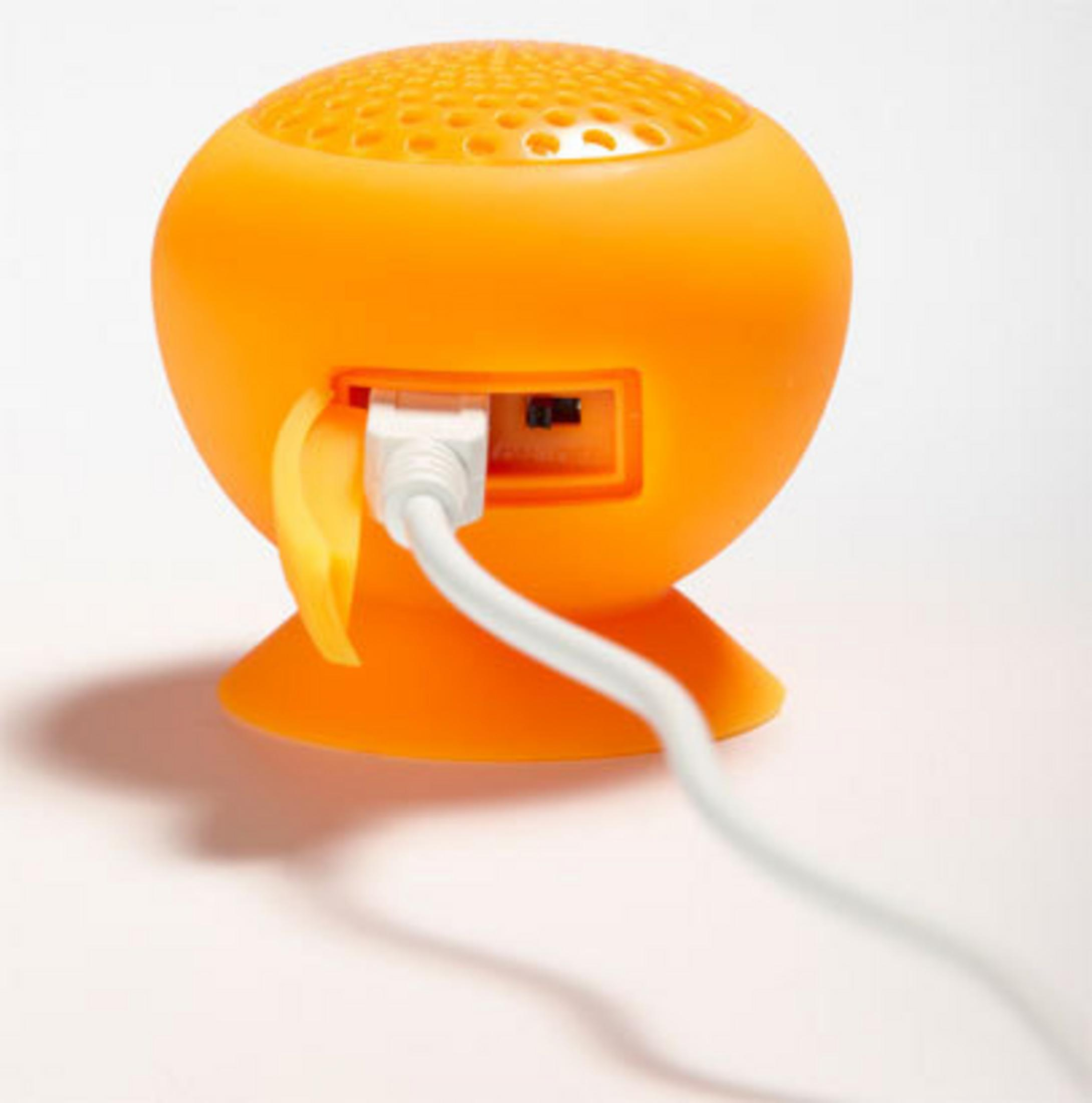 Ein kleiner, oranger Lautsprecher mit einem weißen Kabel, das eingesteckt ist.