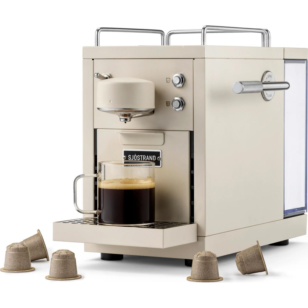 Una macchina da caffè beige con un bicchiere di caffè scuro e diverse cialde.