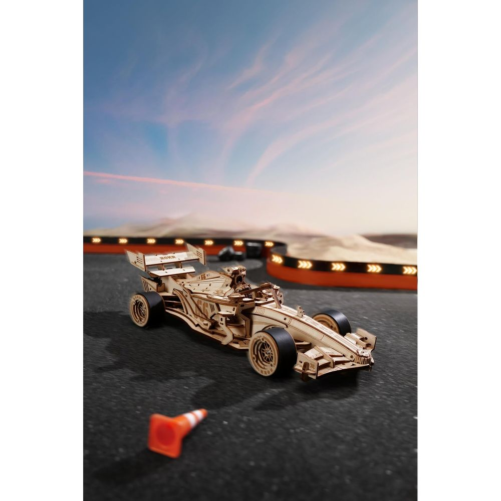 Ein Holzmodell eines Formel-1-Autos auf einer Rennstrecke bei Sonnenuntergang.