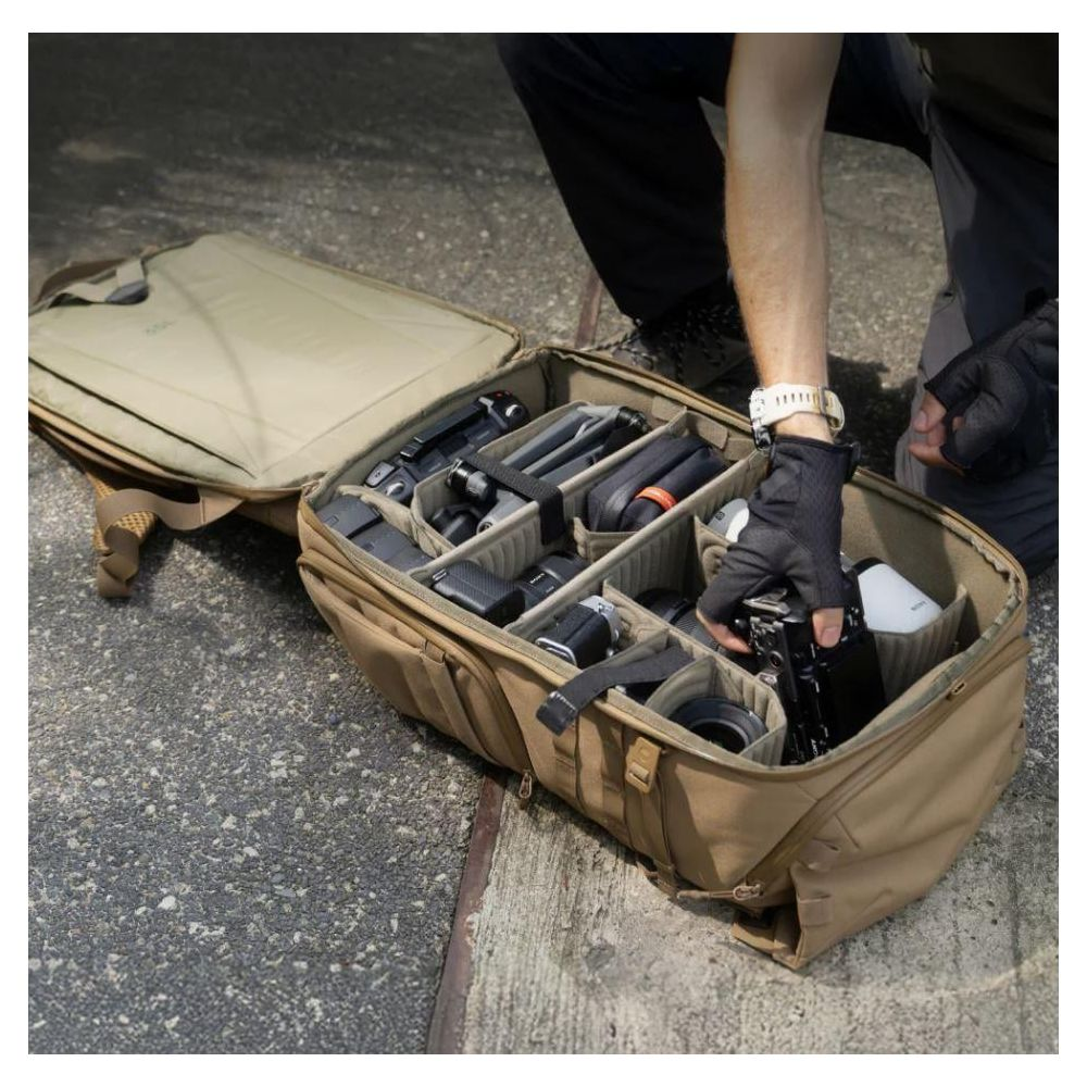 Ein Mann packt Ausrüstung in eine braune Kameratasche mit vielen Fächern.