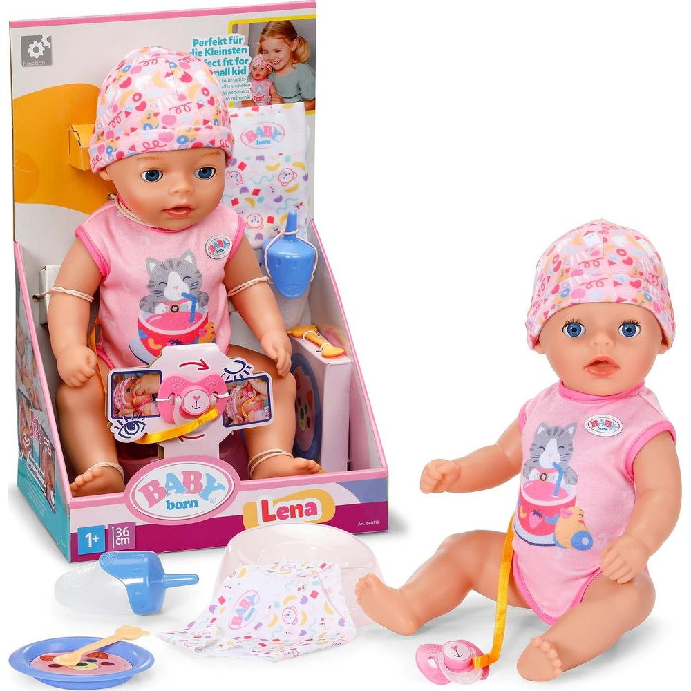 Babypuppe in rosa Outfit mit Katzenaufdruck, neben Karton und Zubehör.