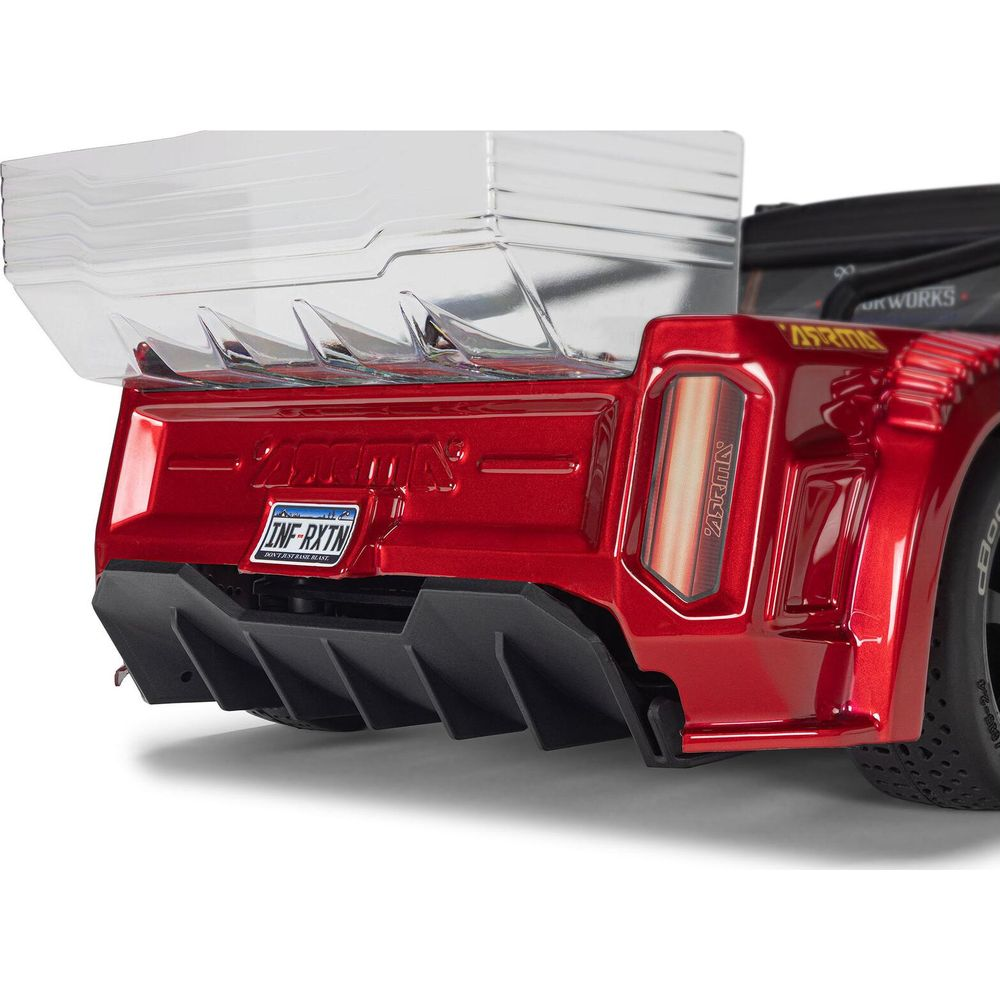 Coche RC rojo con alerón trasero transparente y difusor negro.