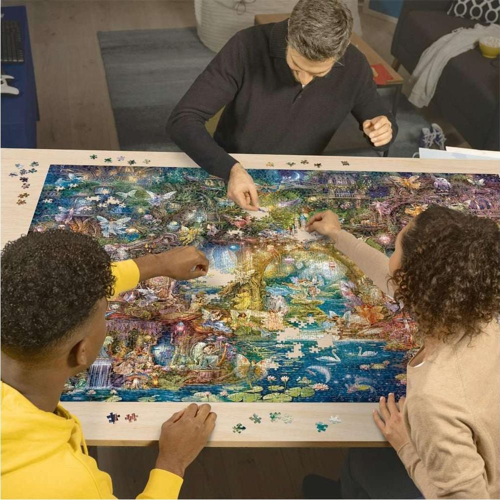 Tre persone assemblano un puzzle dettagliato con una foresta fantasy e un lago.