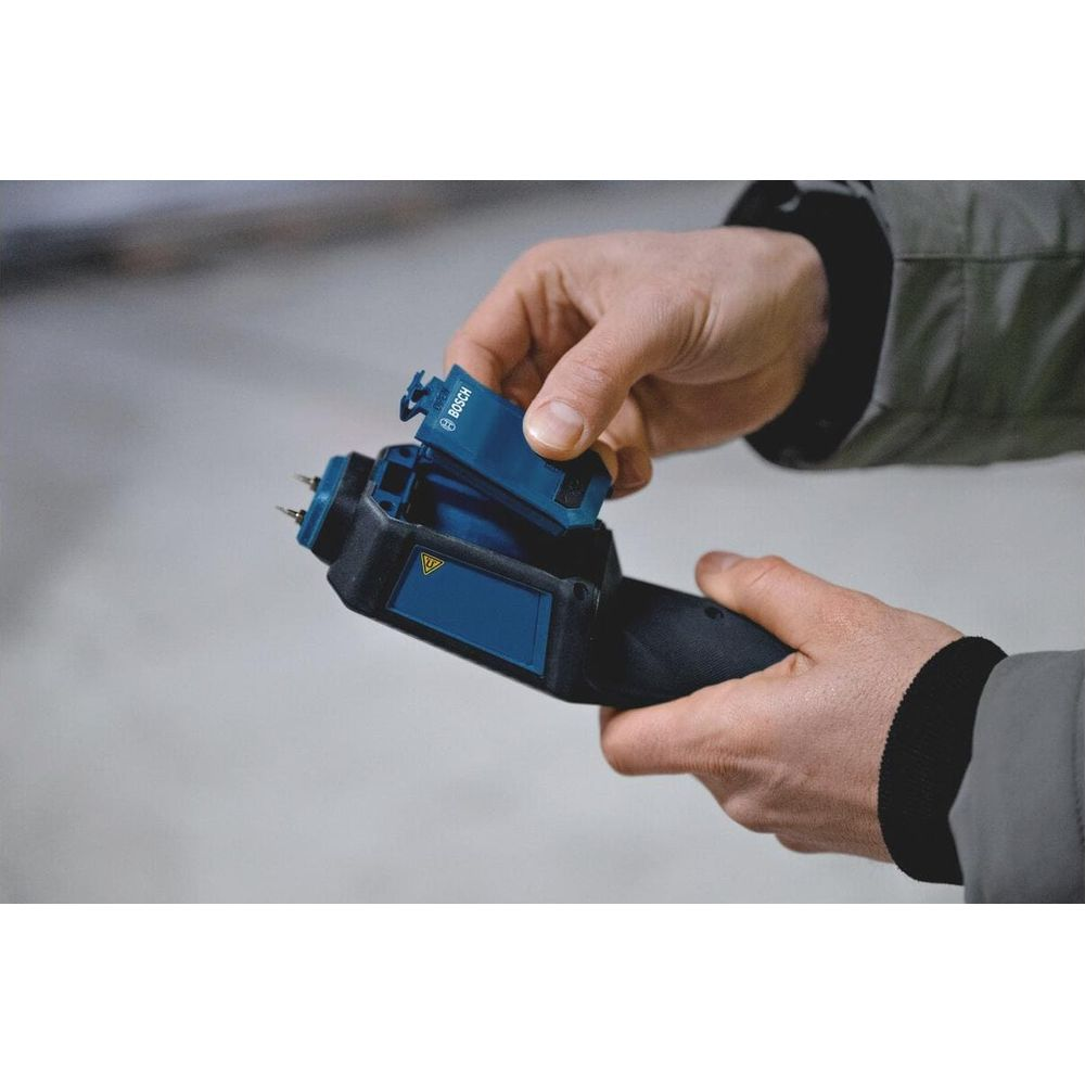 Person setzt eine blaue Bosch-Batterie in ein Messgerät ein.