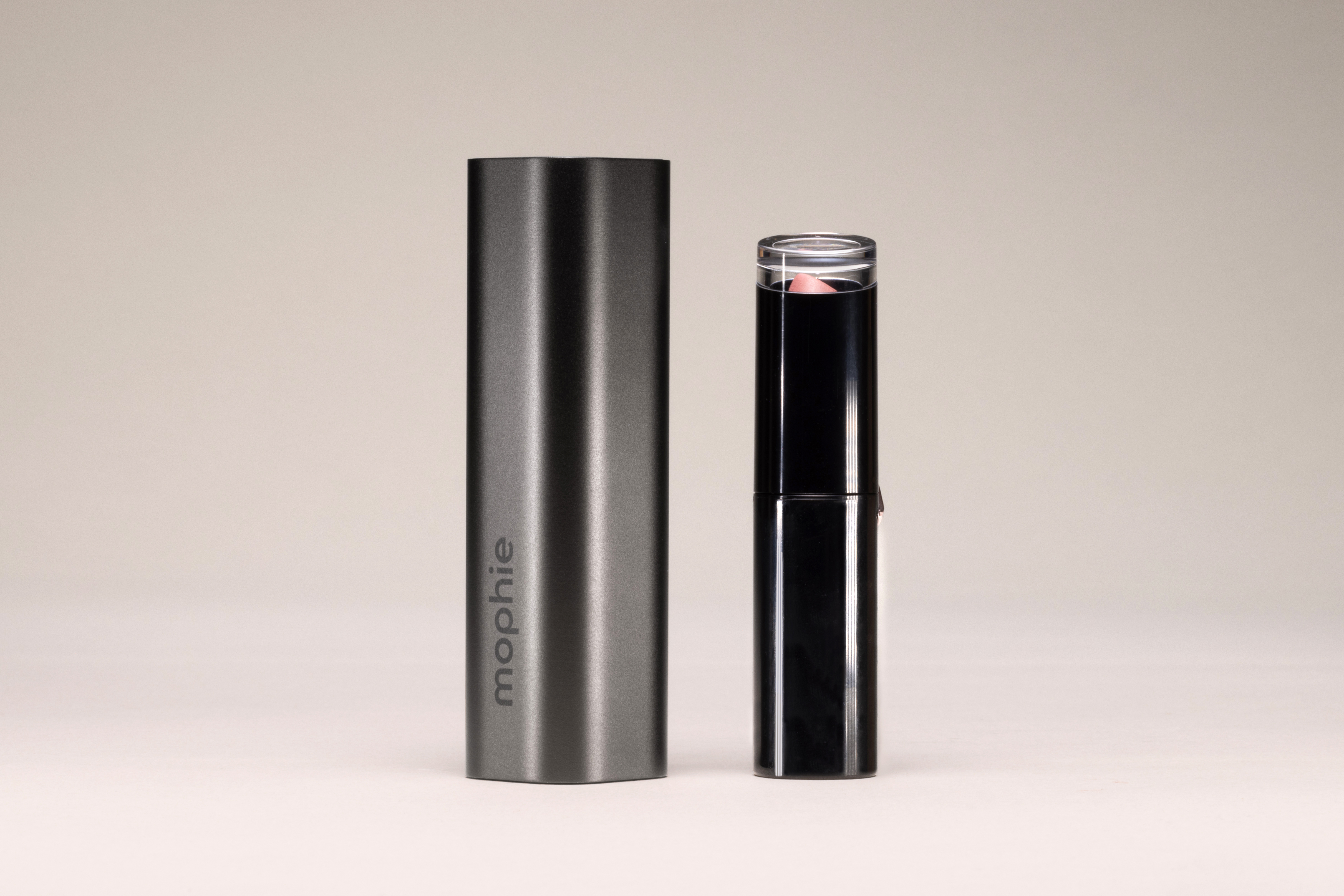 Ein graues Mophie-Etui neben einem rosa Lippenstift in schwarzer Hülle.