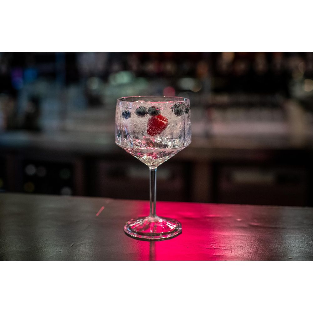 Ein Glas mit Eis, einer Erdbeere und Blaubeeren auf einer Theke.