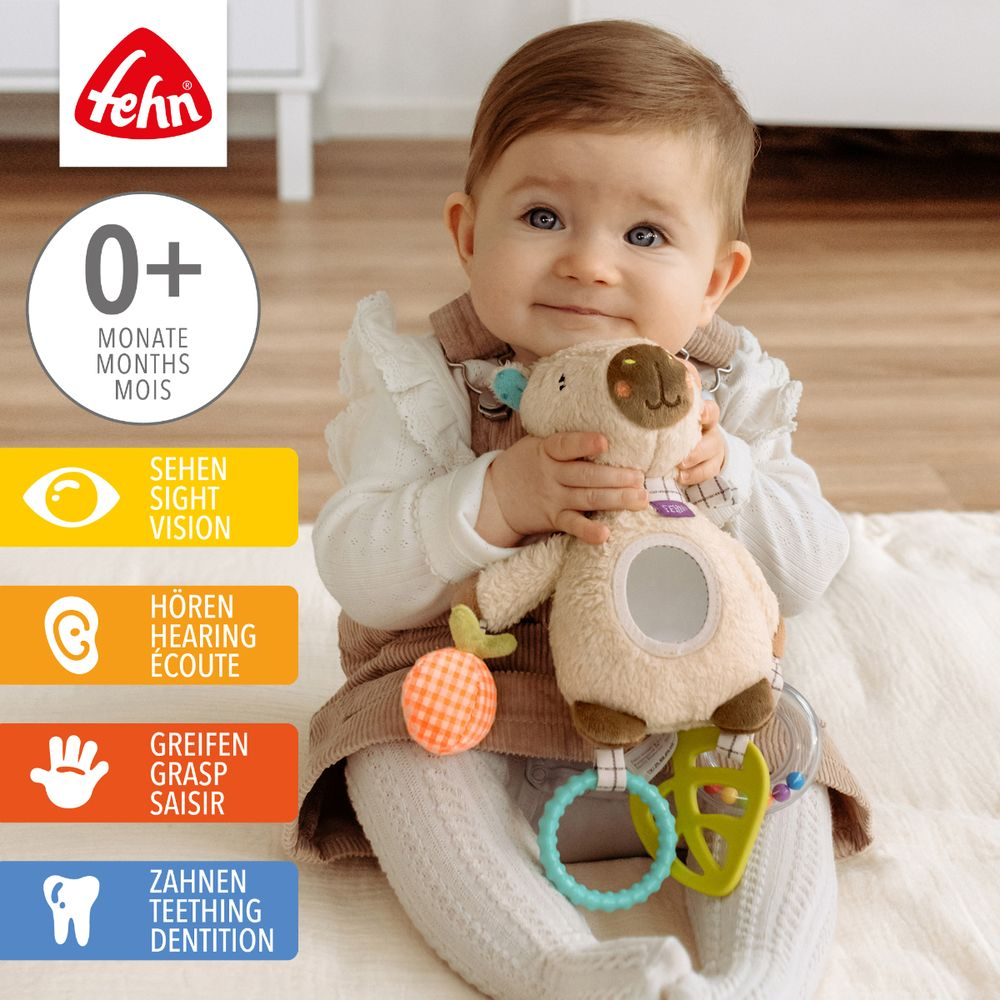 Ein Baby hält einen Teddybär mit Spielzeug. Der "Fehn"-Logo ist oben links.