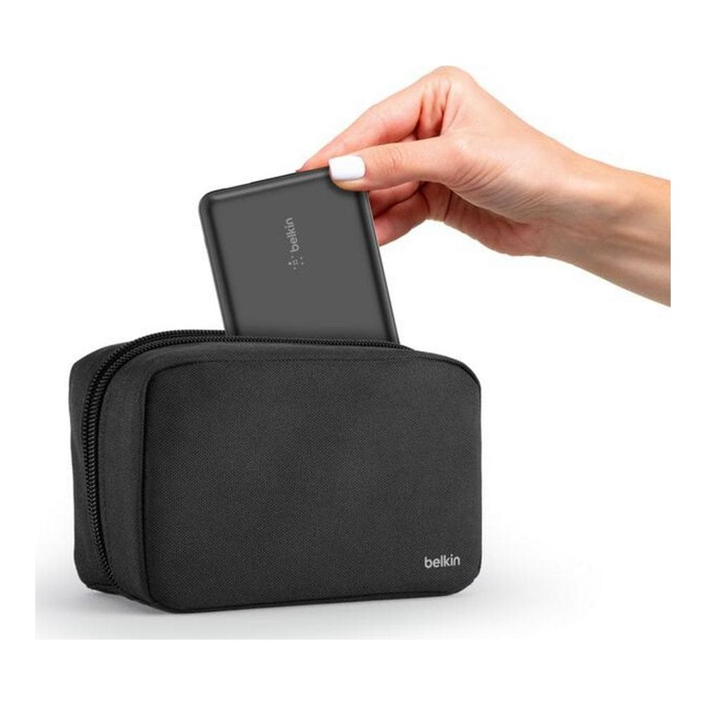 Una mano inserisce un caricabatterie nero in una borsa nera.