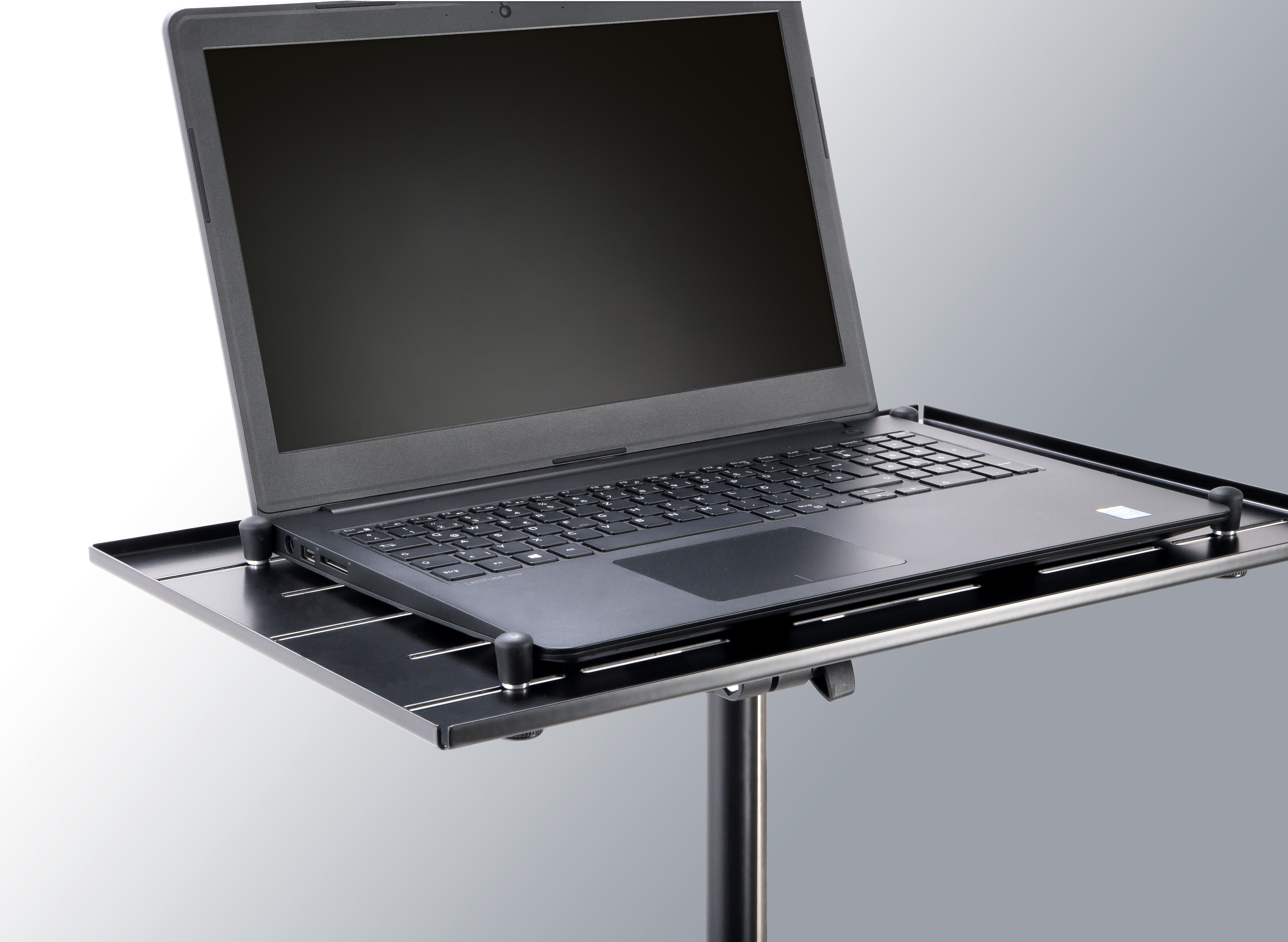Ein schwarzer Laptop auf einem Metallständer mit einem grauen Hintergrund.