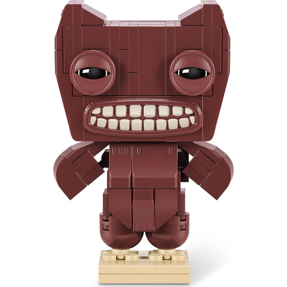 Ein brauner Lego-Charakter mit großen Augen und einem breiten Lächeln steht auf einer beigen Basis.