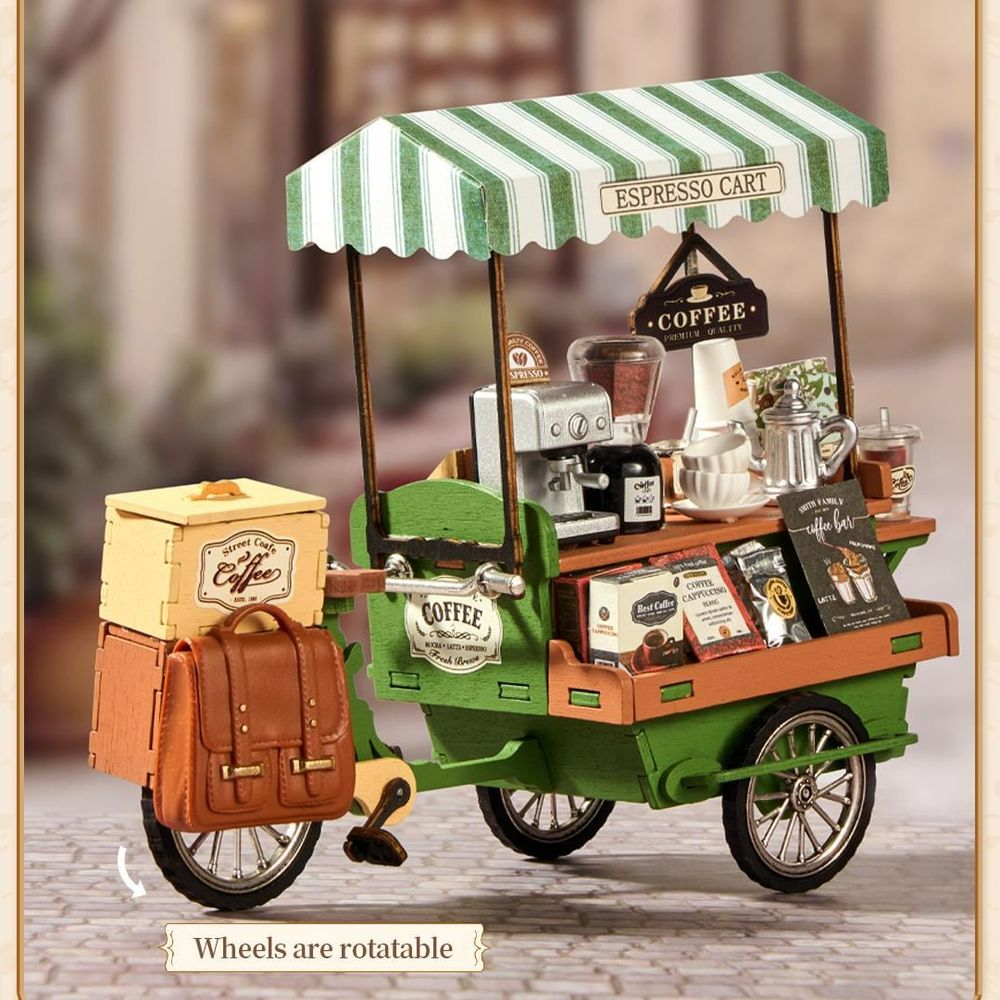 Ein winziger grüner Espresso-Wagen mit gestreiftem Vordach, Kaffeemaschine, Taschen und Tassen.