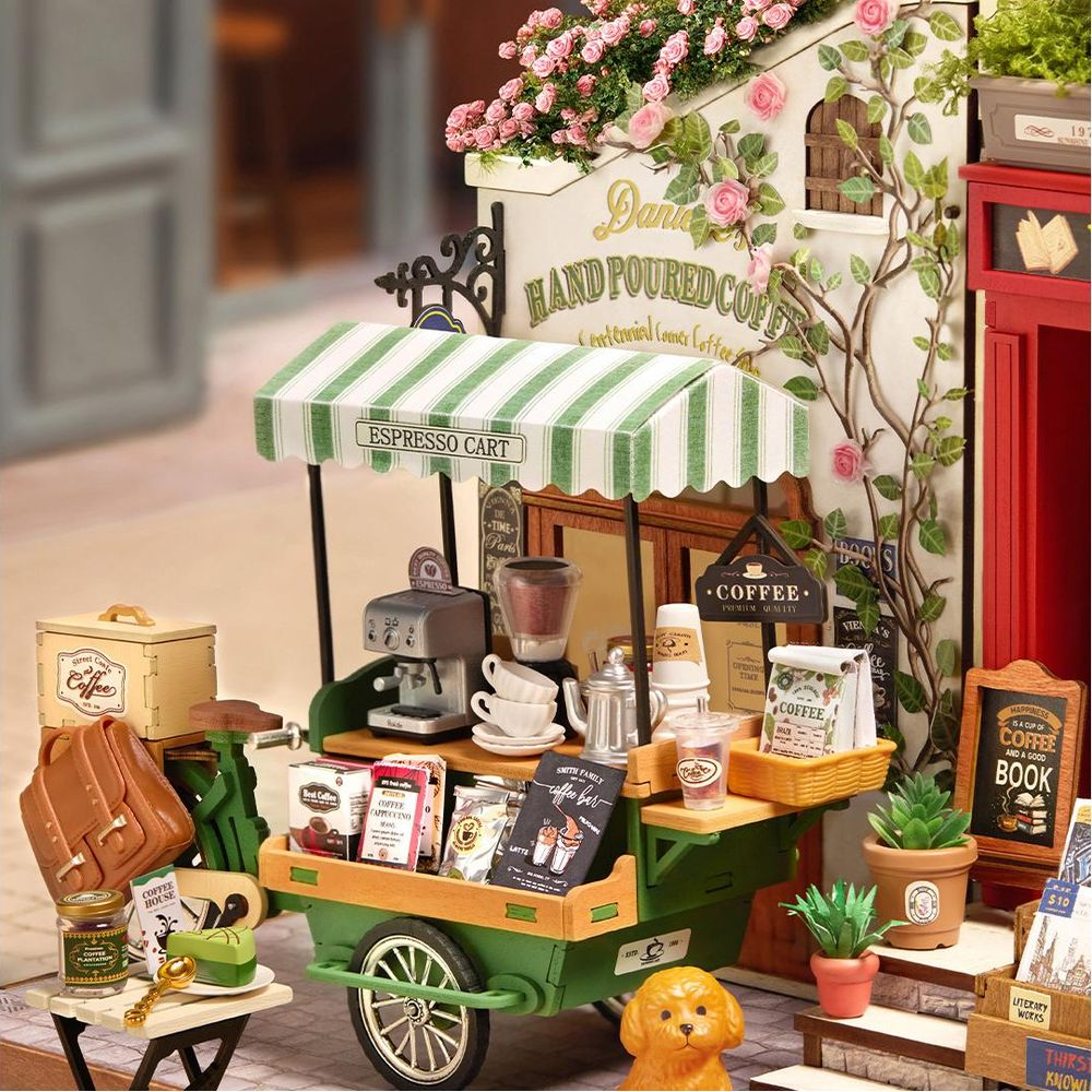 Miniatur-Espressowagen mit Kaffeetüten, Tassen und Pflanzen. Ein Hund sitzt daneben.