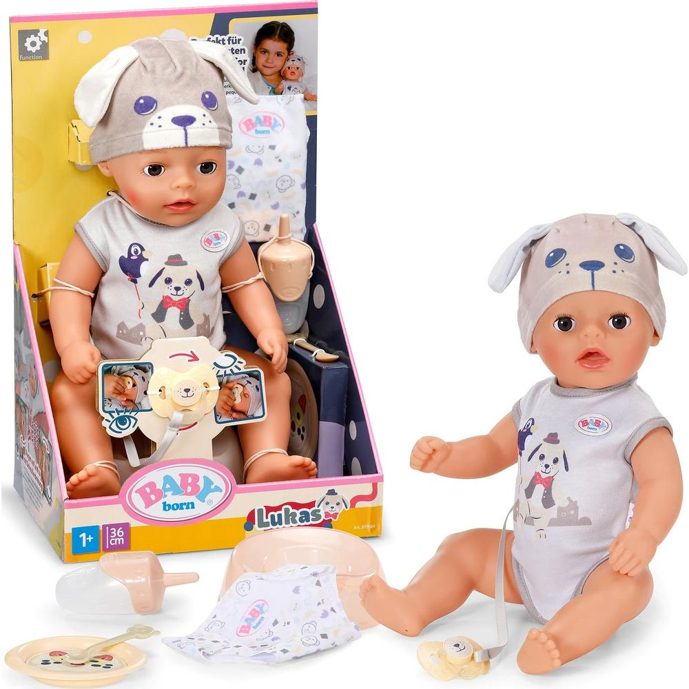 Poupée Baby Born Lukas avec bonnet chien et accessoires en boîte et à côté.
