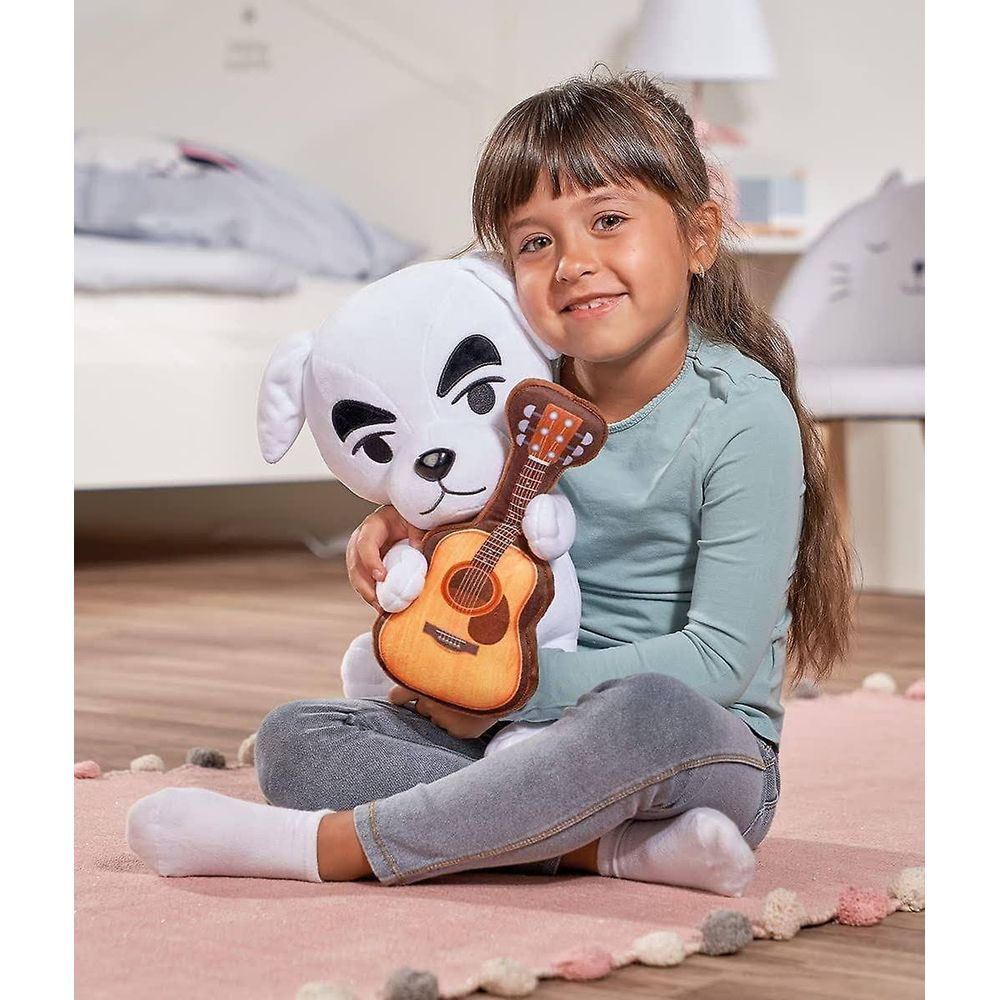 Ein Mädchen sitzt auf einem rosa Teppich und hält einen weißen Hund mit Gitarre.