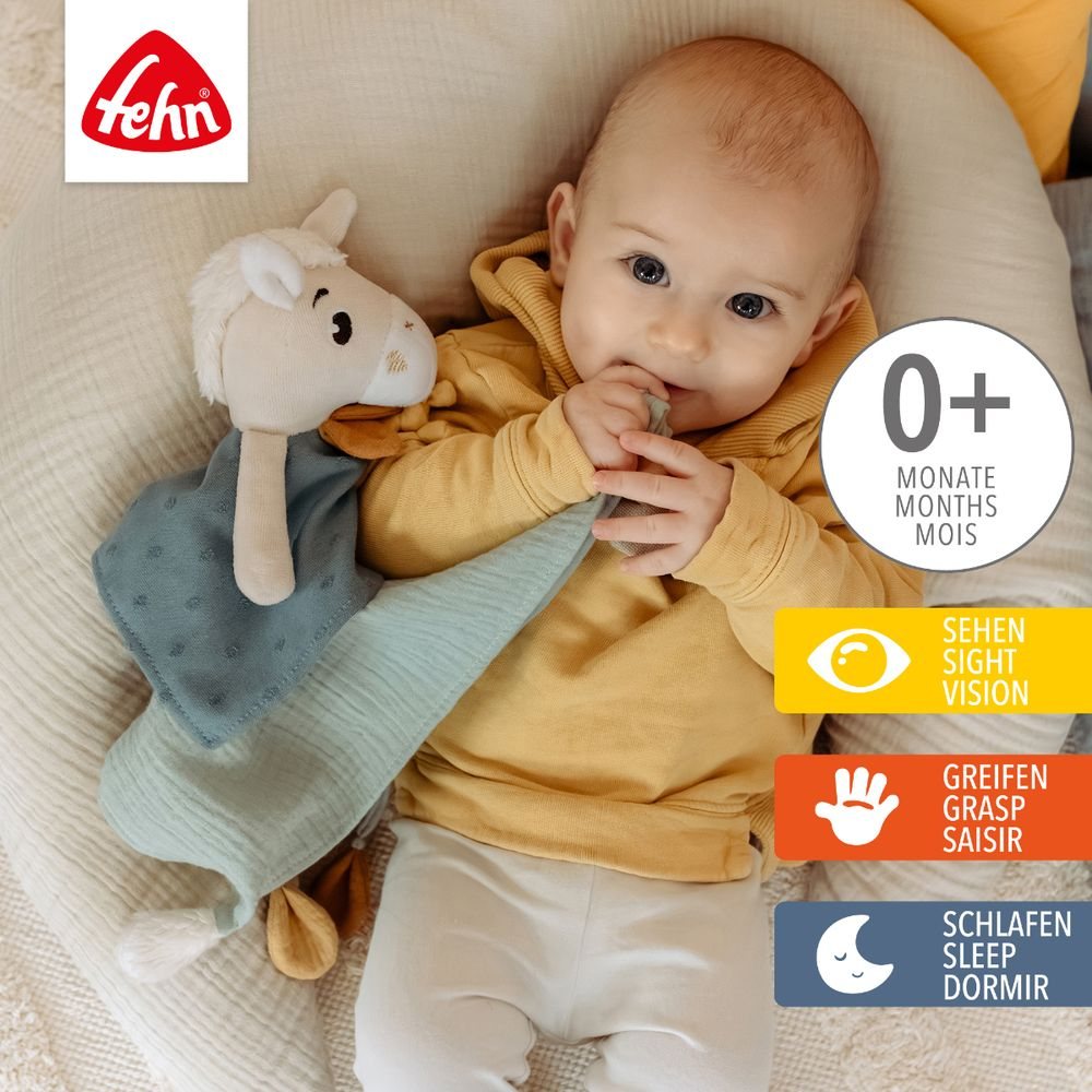 Ein Baby hält einen Schnuffel mit einem Schafkopf und blauen Stoff.