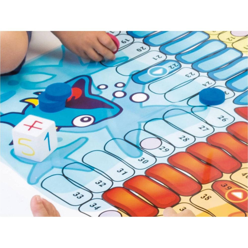 Niños juegan un juego de mesa con temática de tiburón y casillas numeradas.