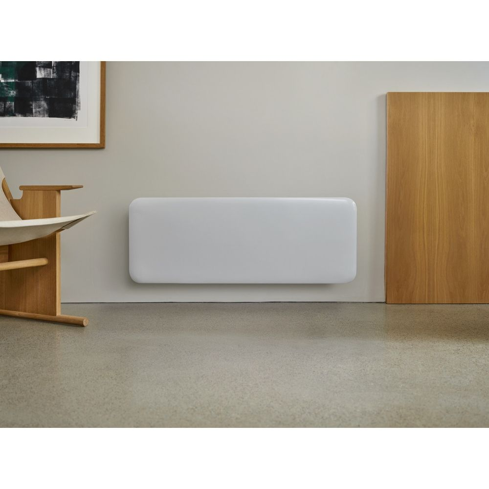Ein weier Heizkörper an einer grauen Wand neben einem Holzelement und Stuhl.