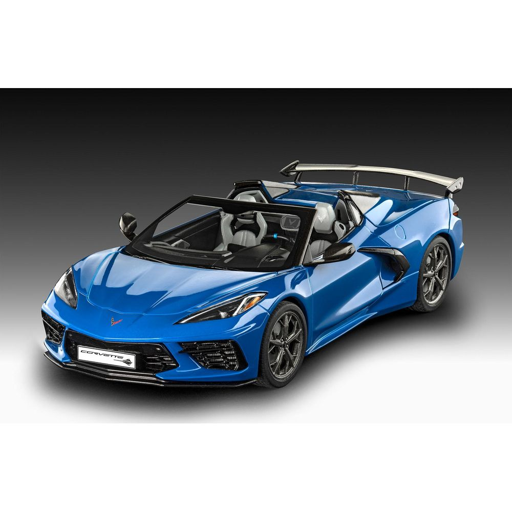Ein blauer Corvette-Cabriolet mit silbernem Spoiler und grauen Sitzen steht auf dunklem Grund.