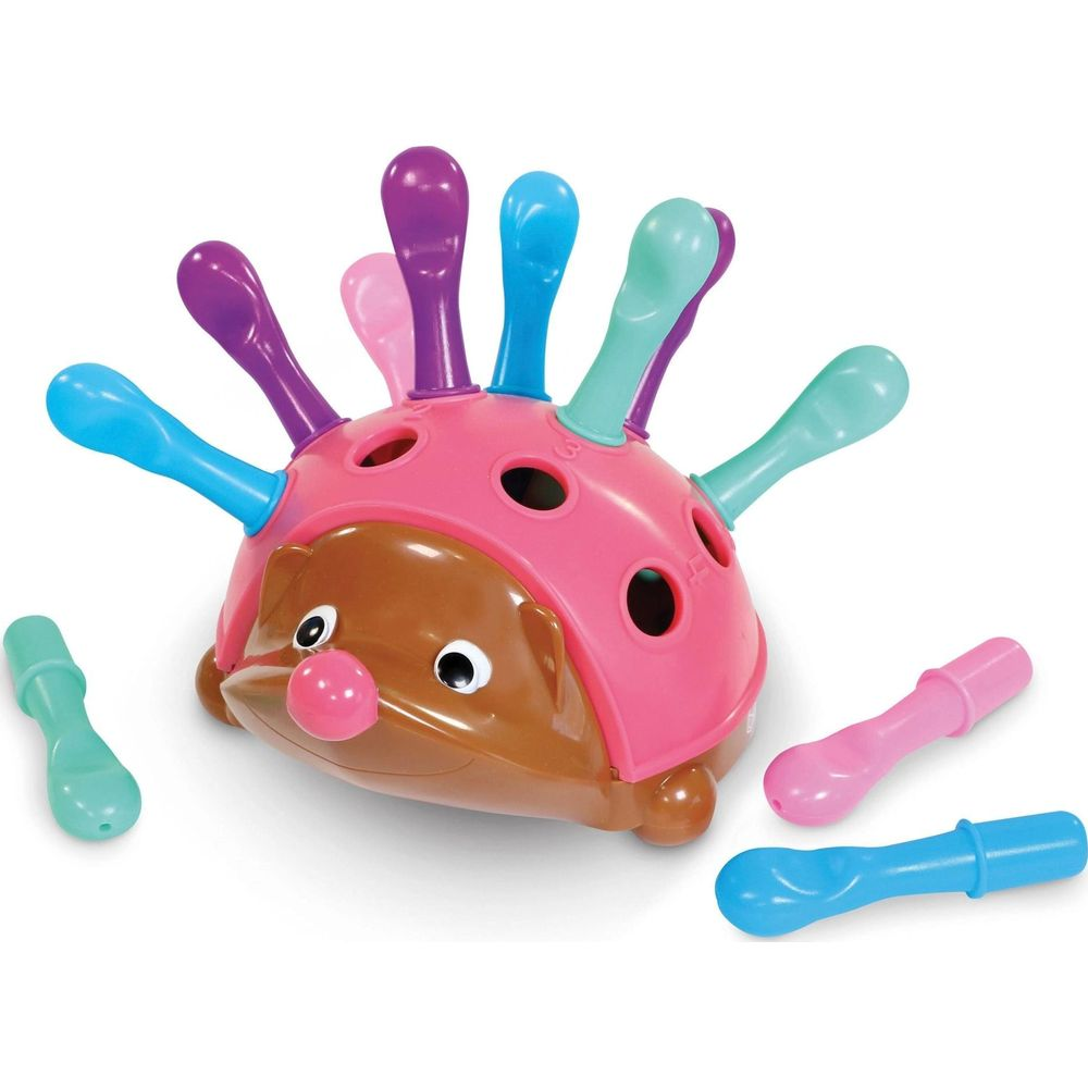 Ein pinker Igel mit braunem Gesicht und bunten Stacheln. Zusätzliche Stacheln liegen daneben.