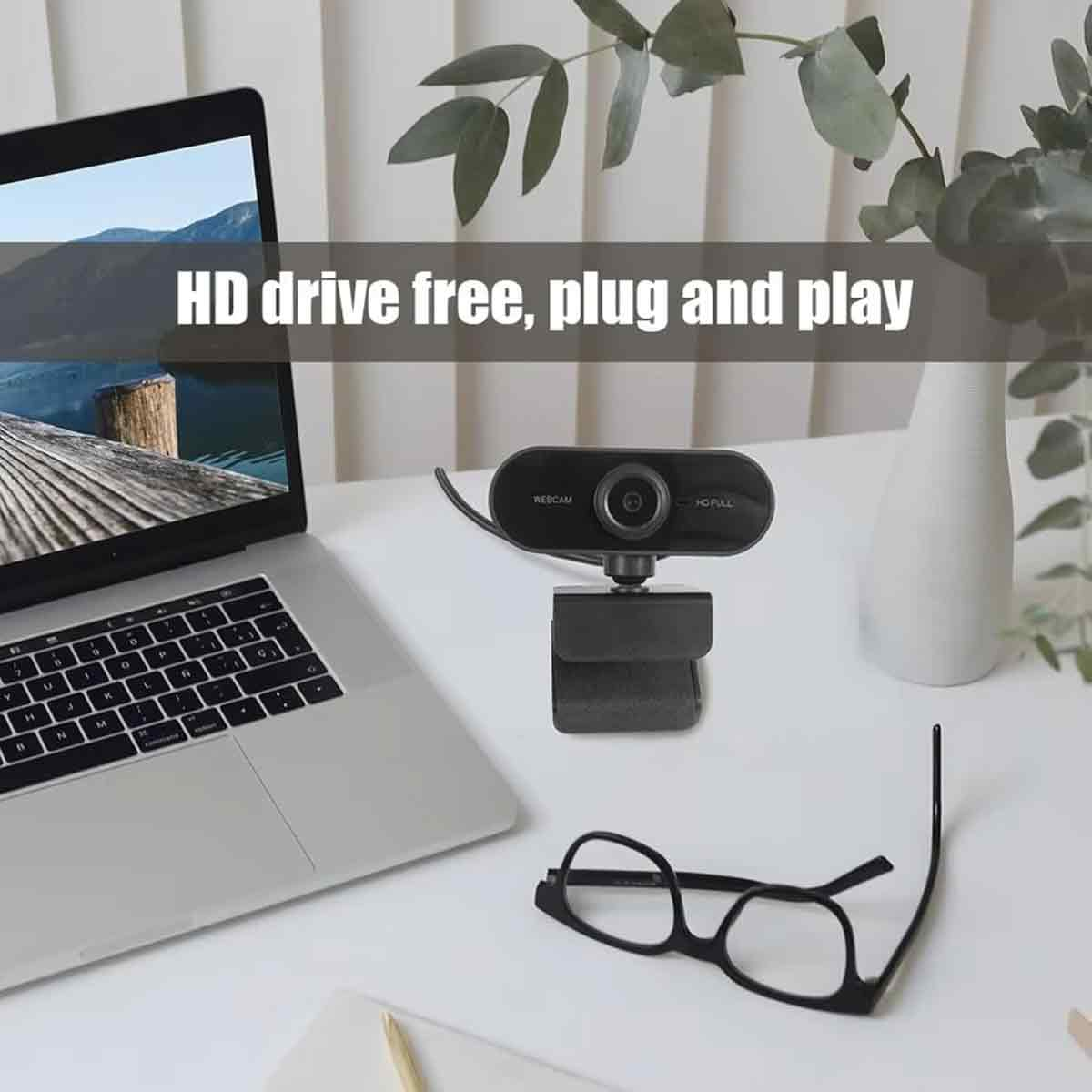 Ein Laptop, eine Webcam, eine Brille und eine Vase stehen auf einem weißen Schreibtisch. Text: HD drive free, plug and play.