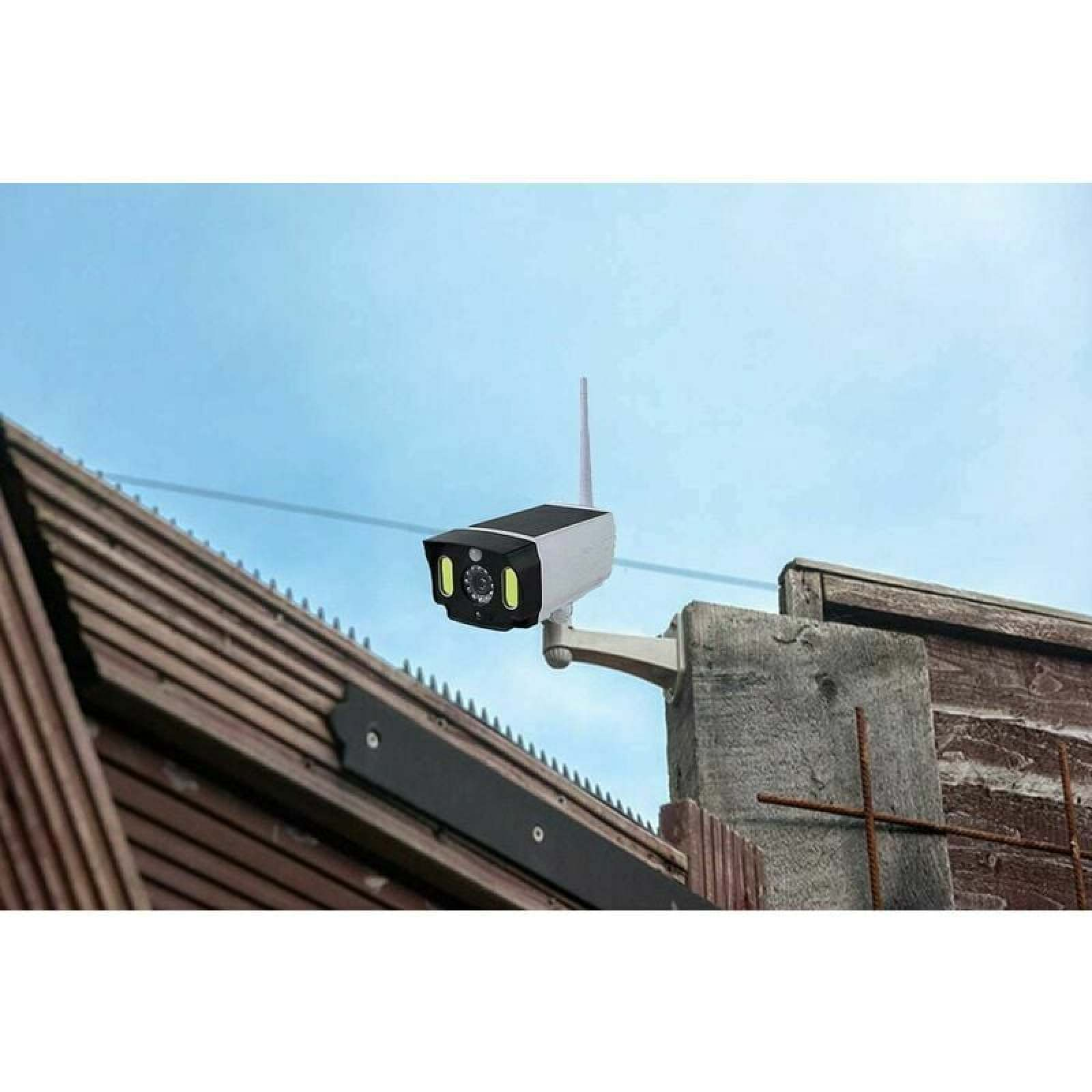 Eine weiße und graue Sicherheitskamera mit Antenne ist an einem Betonpfosten montiert.