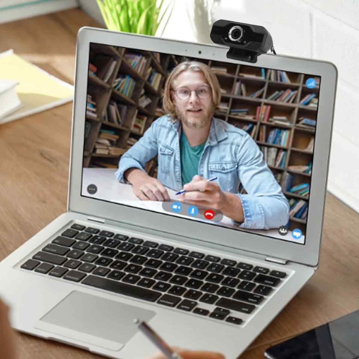 Ein Mann mit Brille im Videoanruf, mit einer Webcam auf einem Laptop.