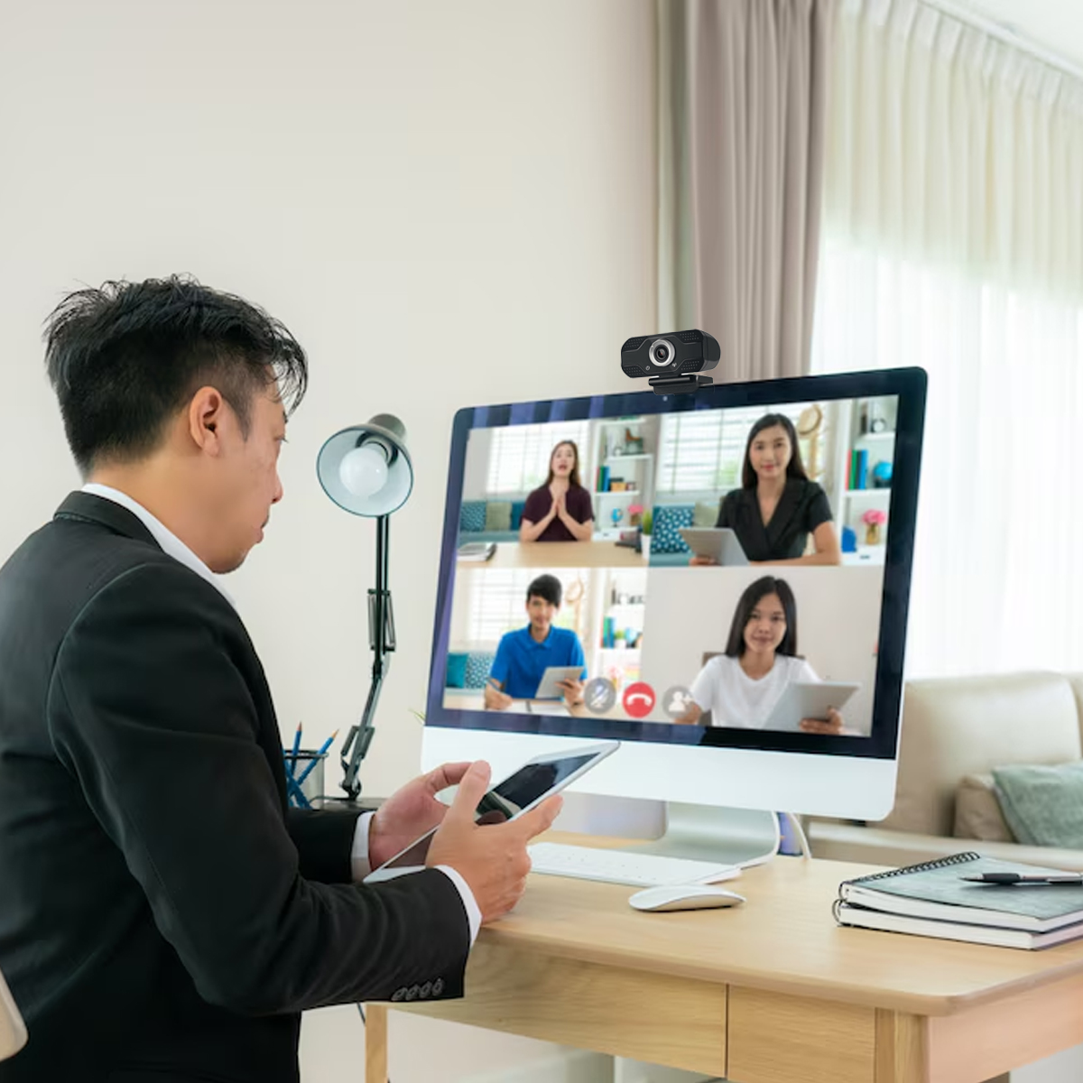 Mann im Anzug bei Videokonferenz mit vier Personen auf dem Bildschirm.