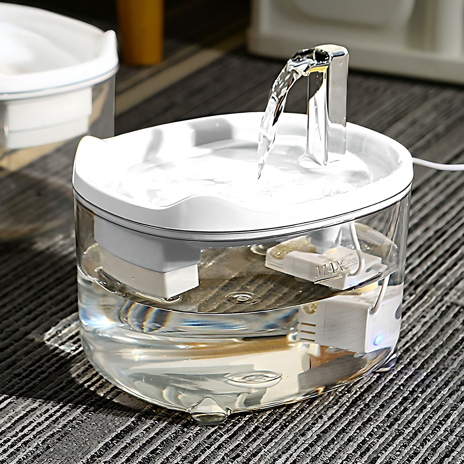 Ein transparenter Trinkbrunnen mit fließendem Wasser und einem MAX-Marker.