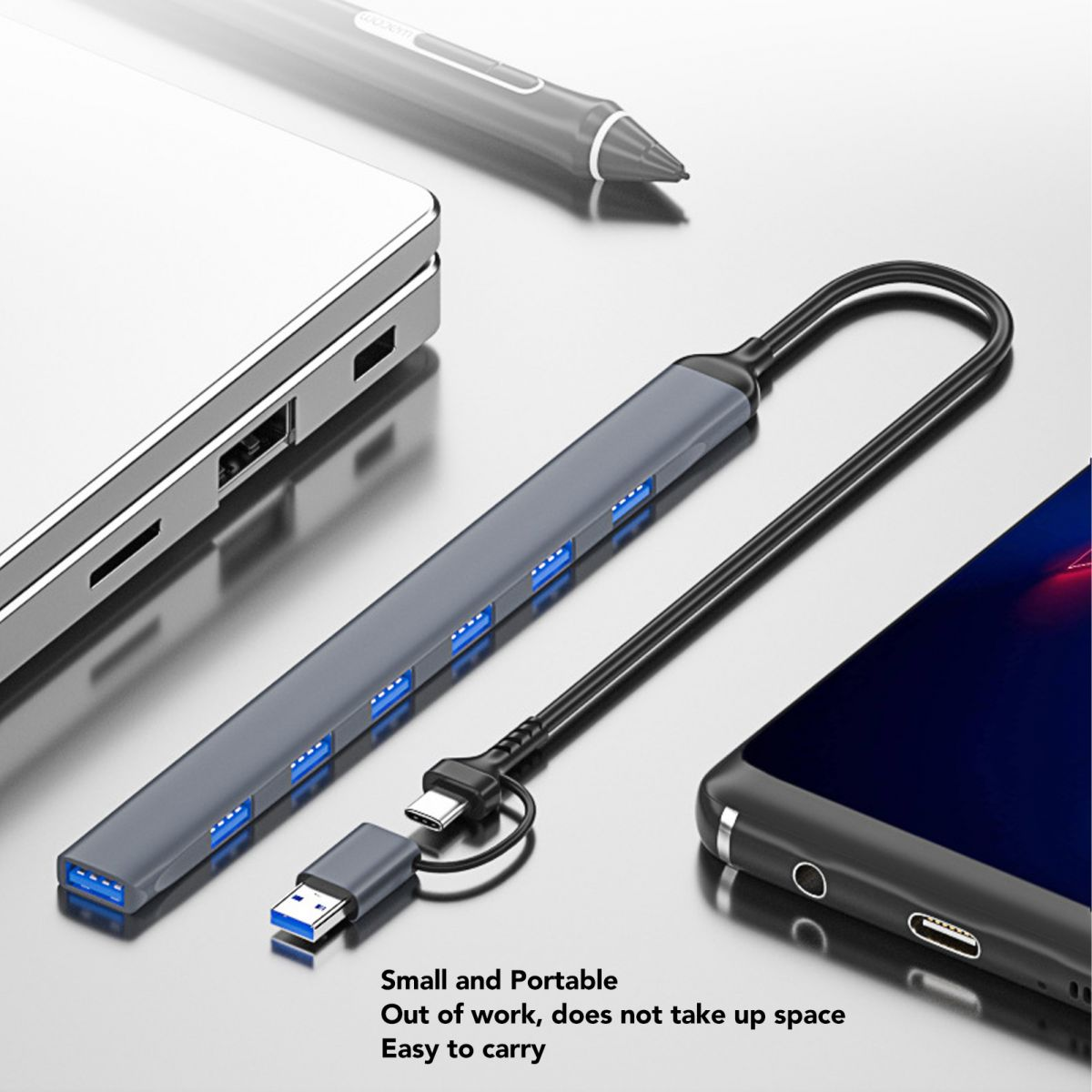 Grauer USB-Hub mit mehreren Anschlüssen, neben Laptop und Smartphone.