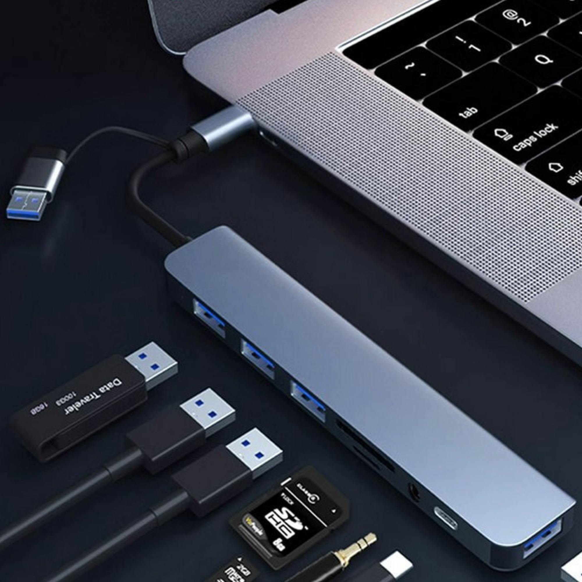 Ein USB-C-Hub mit mehreren Anschlüssen, verbunden mit einem Laptop, neben USB-Sticks.