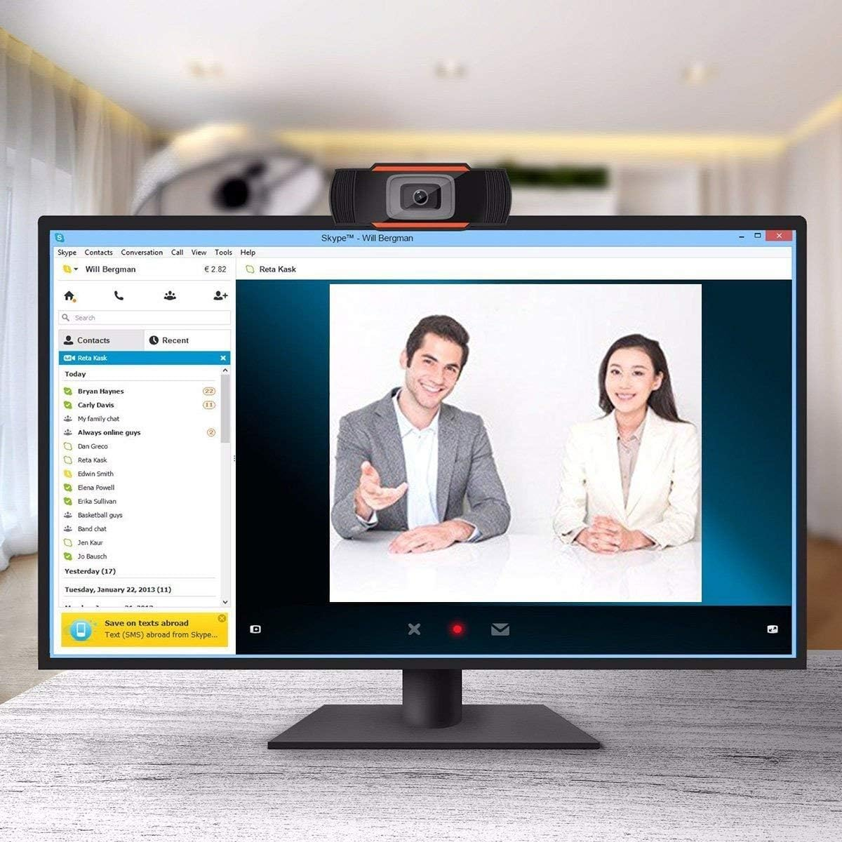 Ein Mann und eine Frau sitzen vor einem Computer mit Skype-Anwendung, eine Webcam ist montiert.