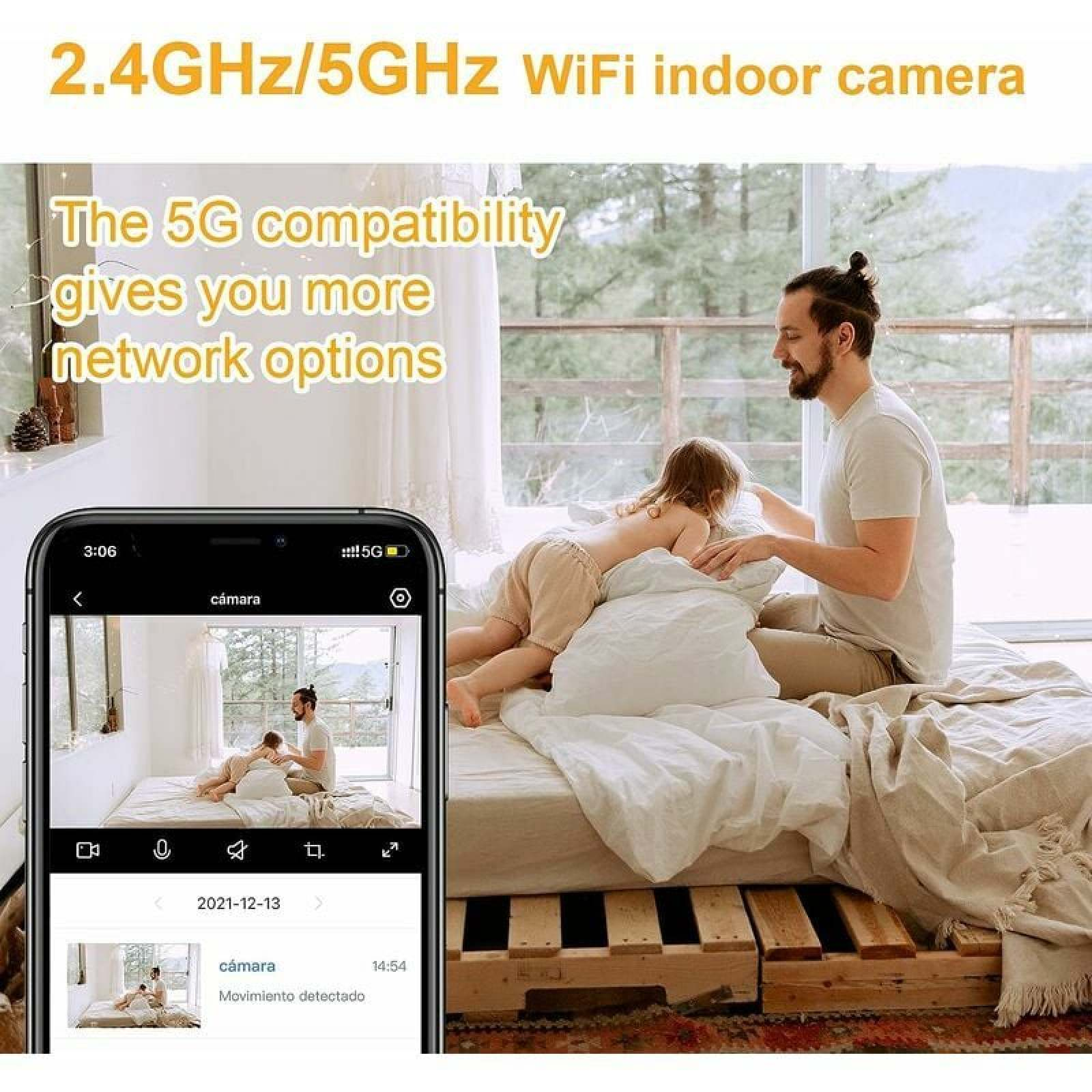 Ein Mann und ein Kind spielen auf einem Bett, ein Handy zeigt die Kameraansicht.