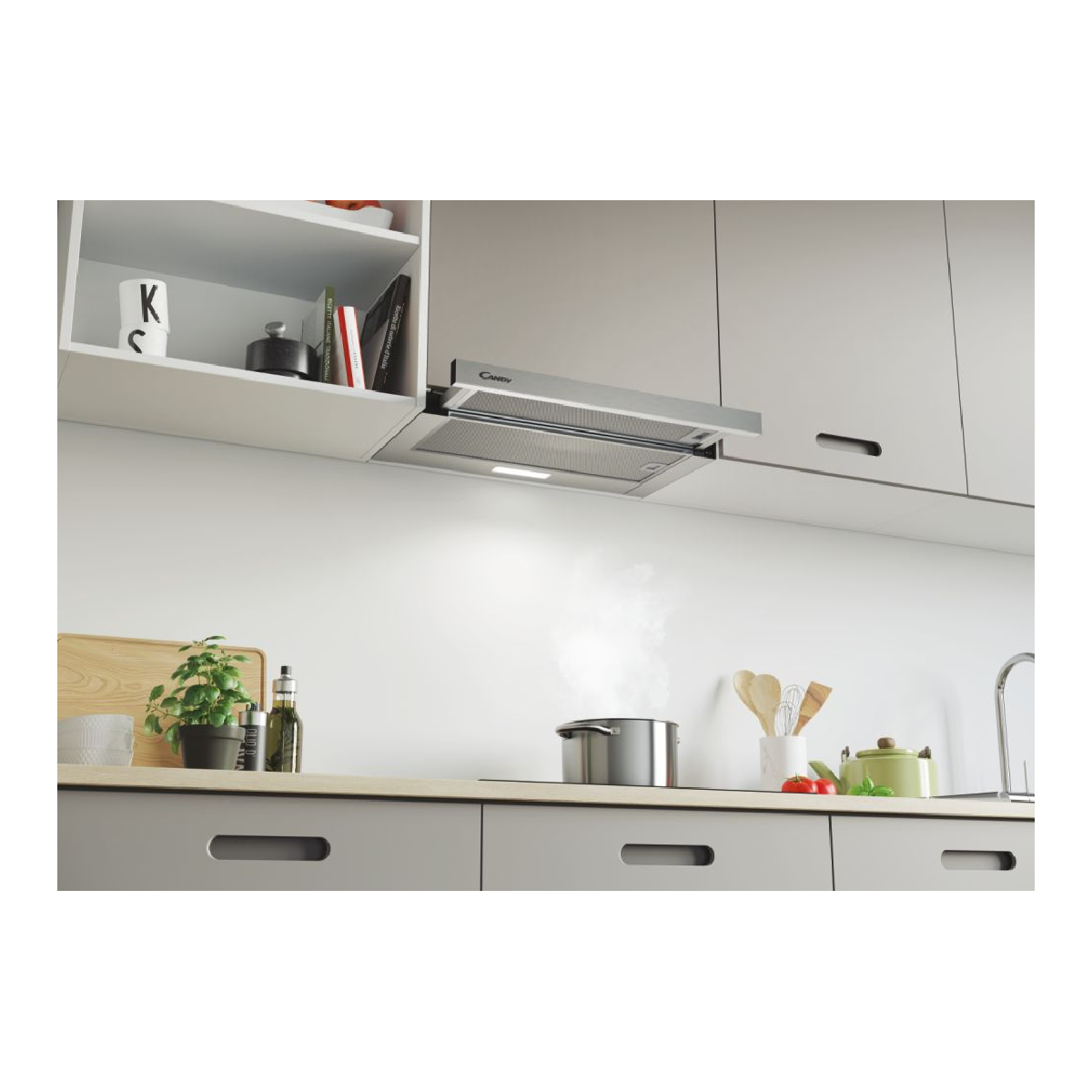Una pentola emana vapore su un fornello sotto una cappa in una cucina moderna.
