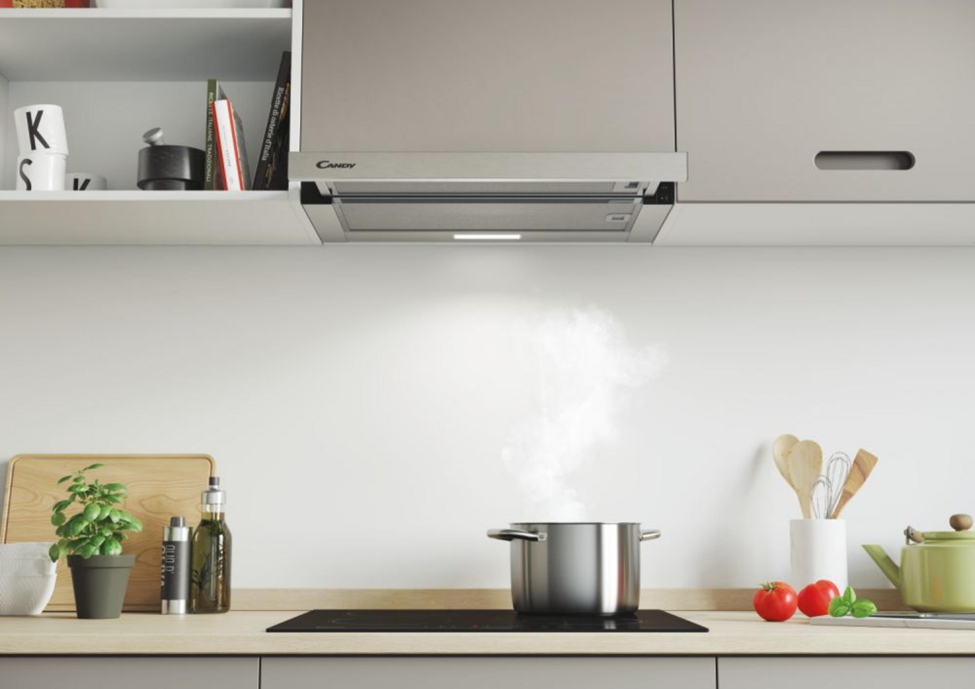 Una pentola argentata emana vapore su un piano cottura a induzione nero in una cucina moderna.