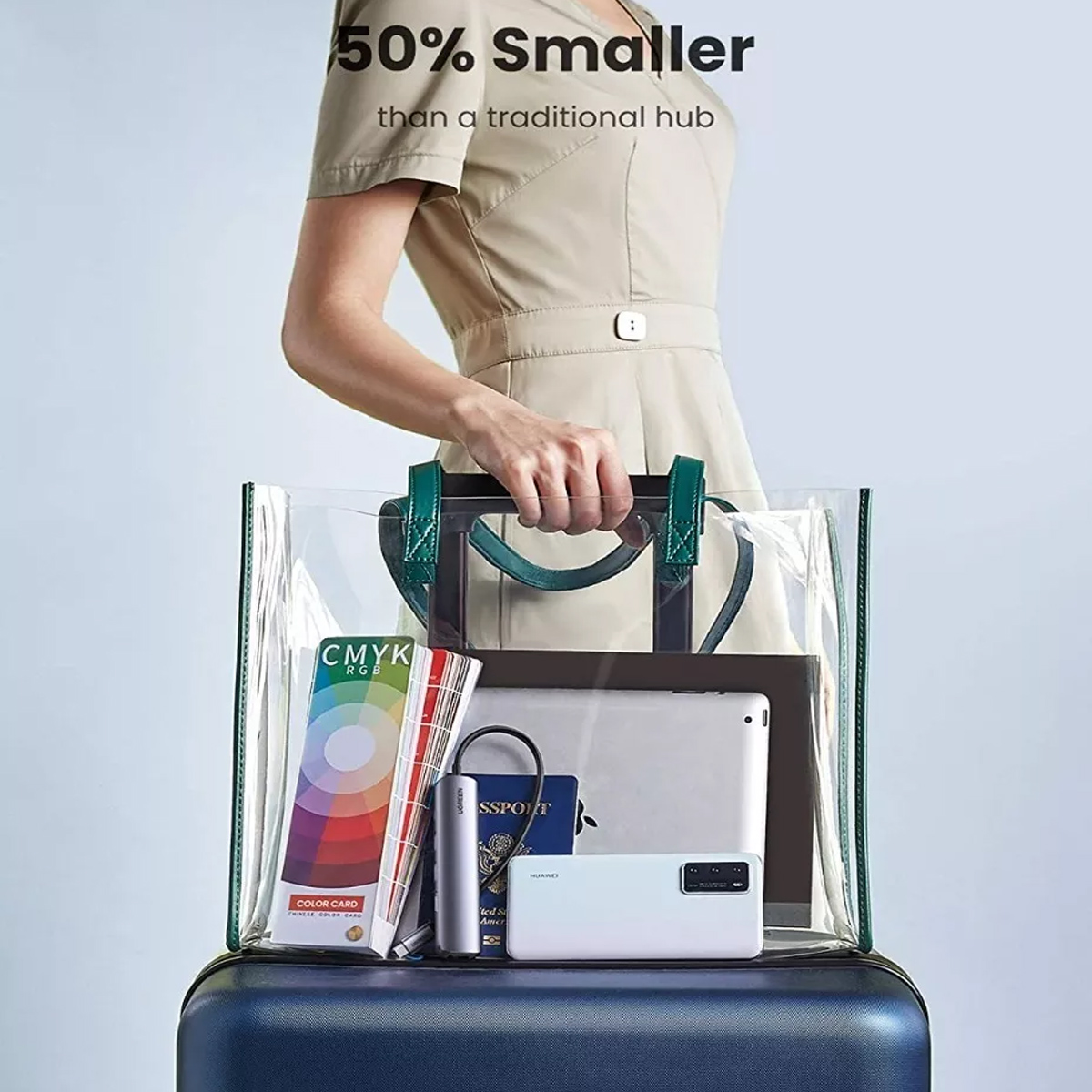 Eine Frau hält eine durchsichtige Tasche mit einem Tablet, Reisepass, Handy, Farbkarten und einem Hub.