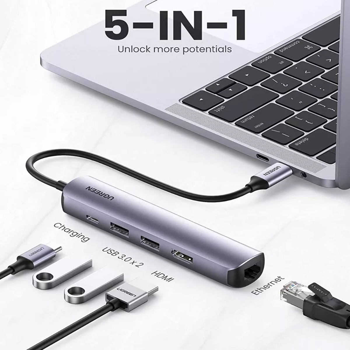 Ein grauer USB-C-Hub mit Anschlüssen für Lade, USB 3.0, HDMI und Ethernet, angeschlossen an einen Laptop.