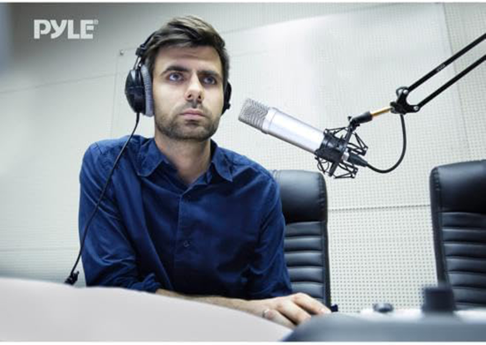 Ein Mann mit Kopfhörern sitzt vor einem Mikrofon im Studio.