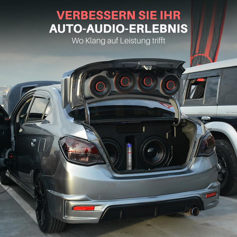 Ein graues Auto mit geöffnetem Kofferraum, gefüllt mit Lautsprechern und Subwoofern.