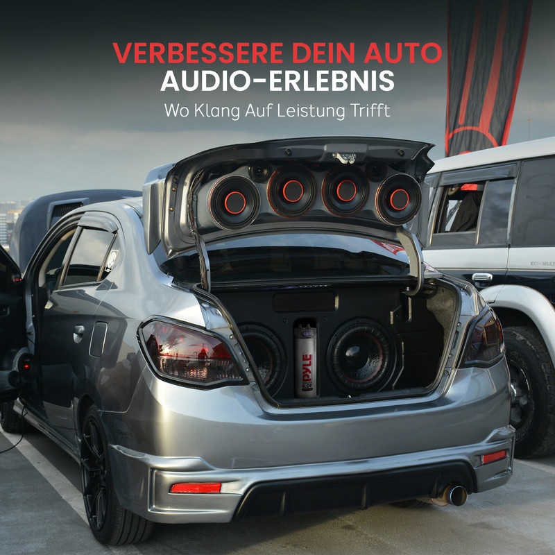 Ein silberner Wagen mit geöffnetem Kofferraum voller Lautsprecher und einem Subwoofer.
