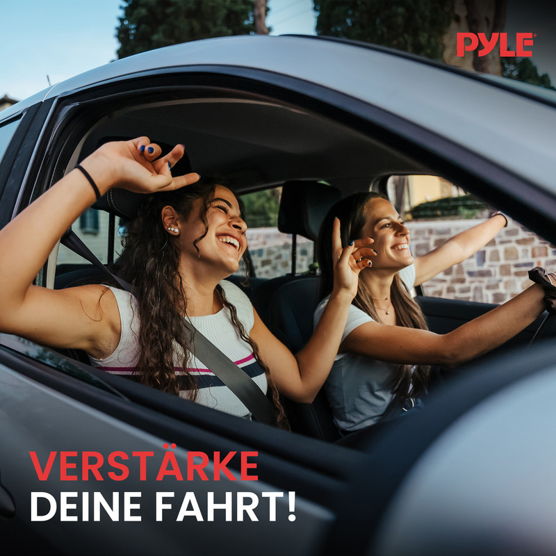 Zwei junge Frauen fahren lachend im Auto, eine winkt aus dem Fenster.