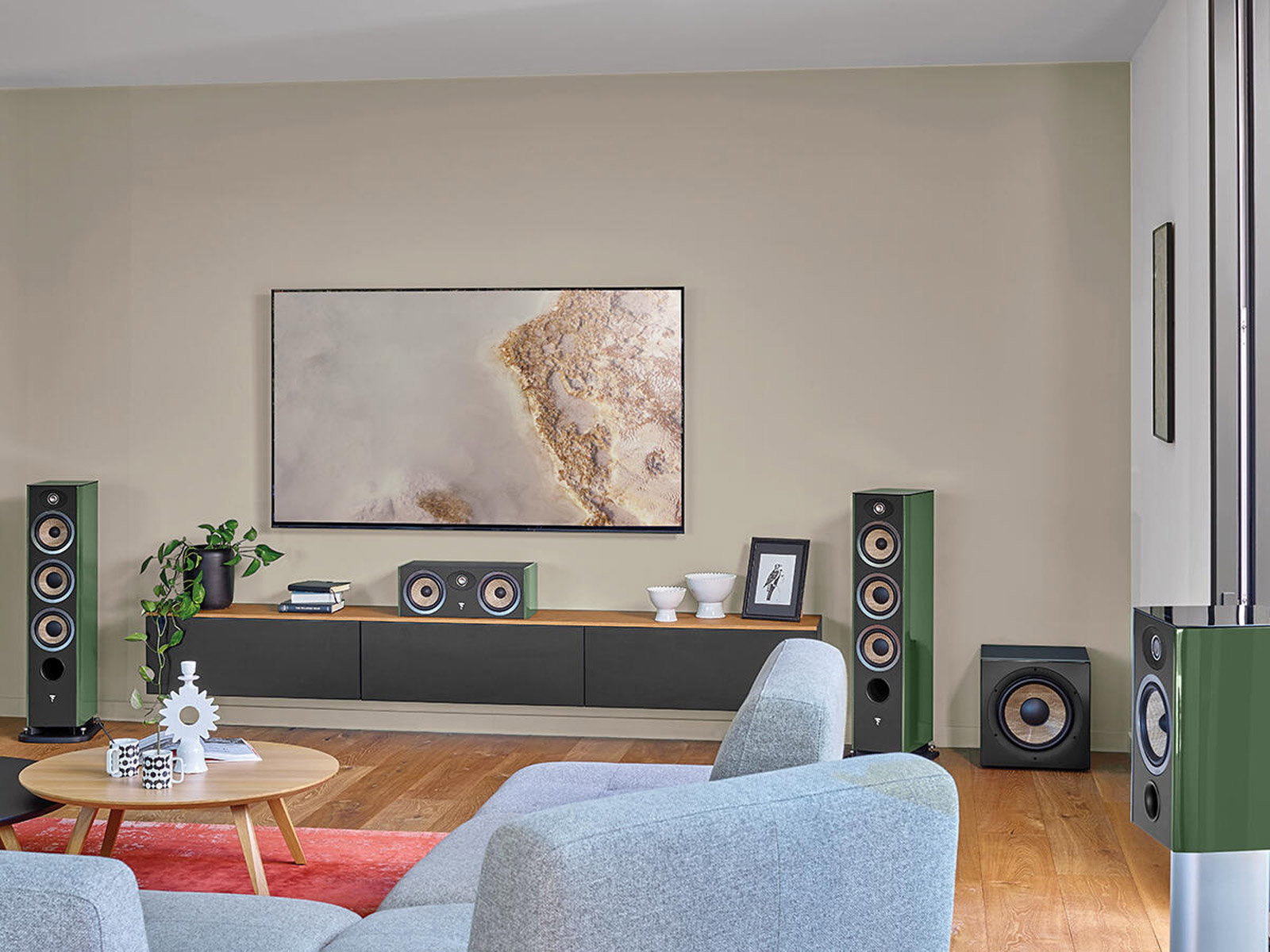 Ein Wohnzimmer mit grünen Lautsprechern, Fernseher und Möbeln auf Holzboden.