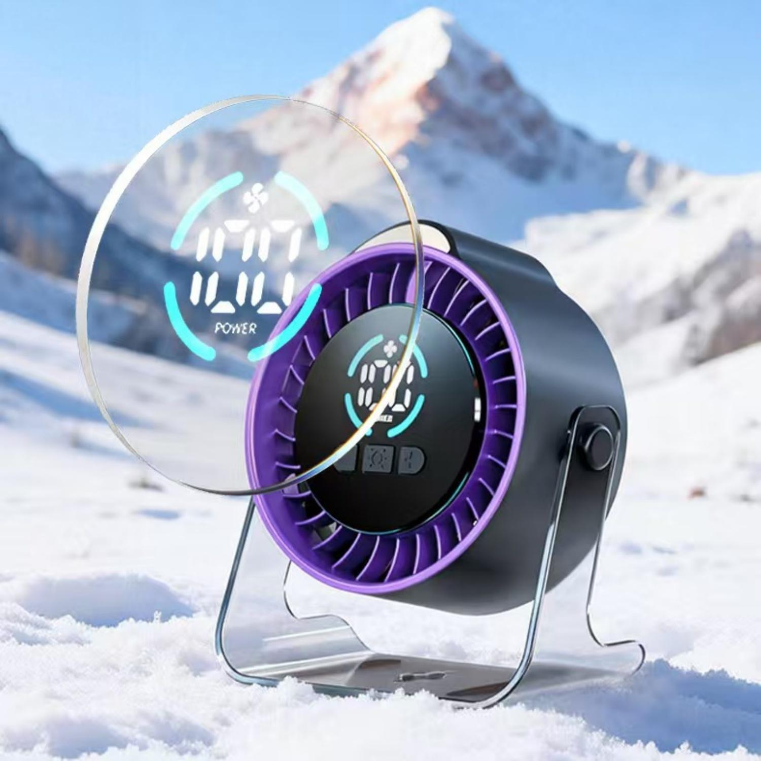 Ein tragbarer Lüfter mit digitaler Anzeige steht im Schnee vor verschneiten Bergen.