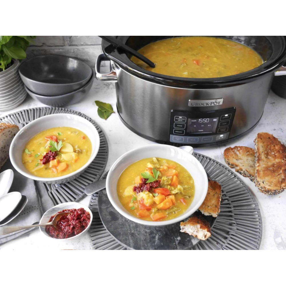 Crock-Pot z zupą, dwie miski zupy i chleb na stole.